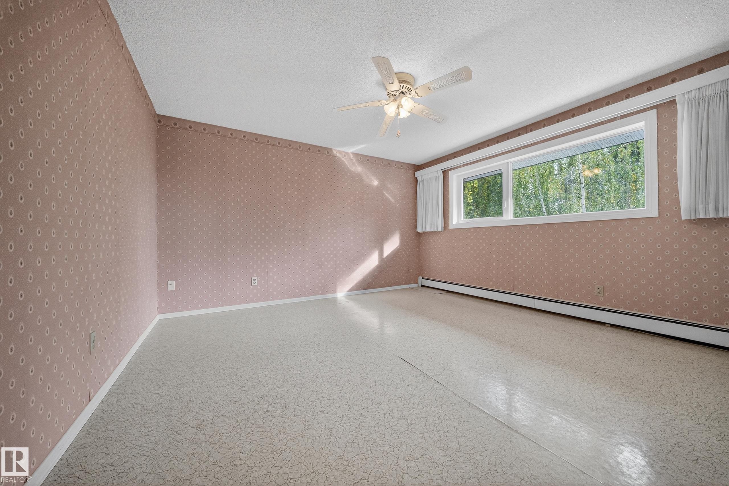 Spacious room featuring patterned wallpaper, a textured ceiling, and patterned resilient flooring - 707 65 Avenue, Edmonton, AB