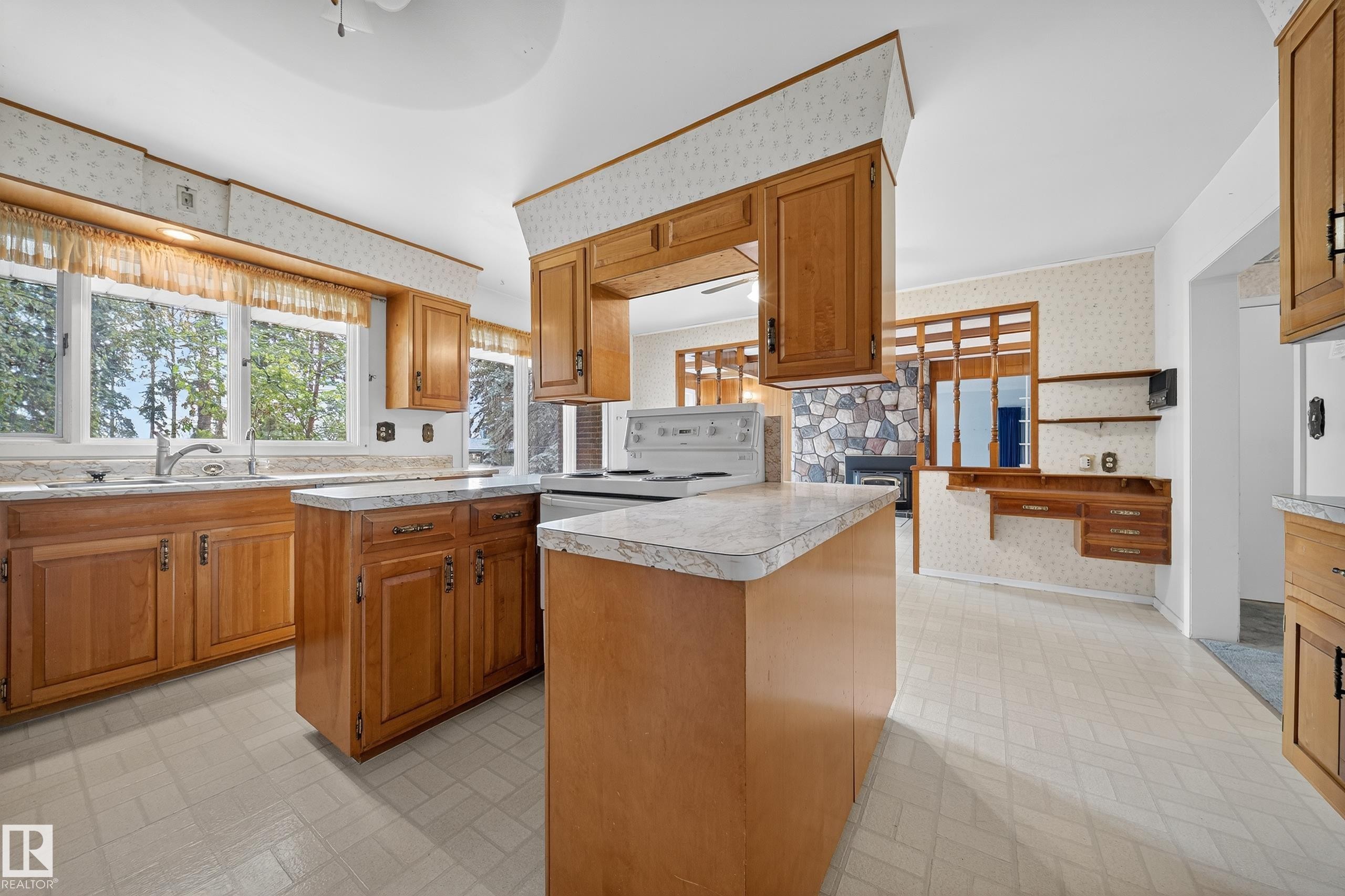 Kitchen featuring wood cabinetry, white appliances, a center island, and a sink beneath a large window - 707 65 Avenue, Edmonton, AB