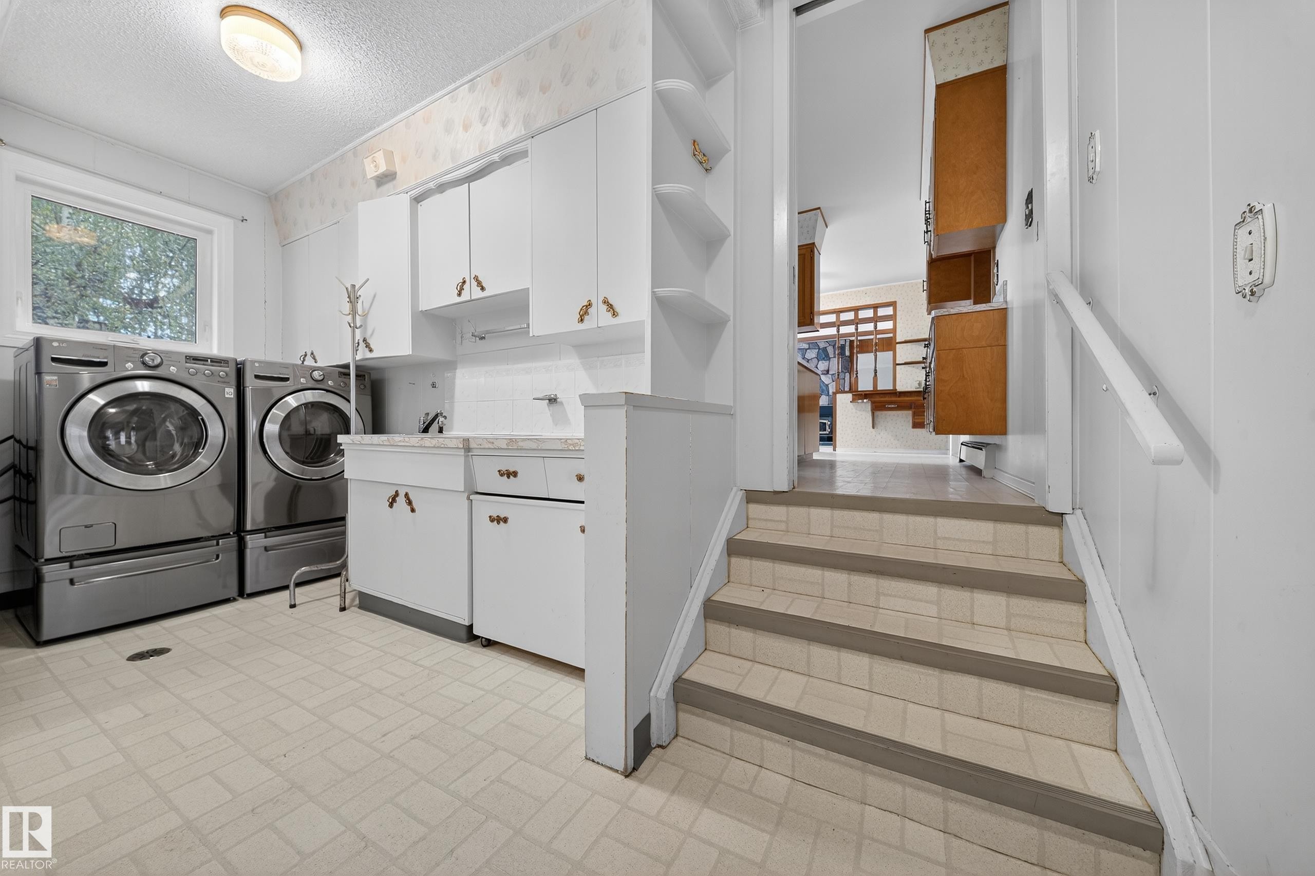Dedicated laundry area featuring a window, built-in cabinetry, a utility sink, and wall shelving - 707 65 Avenue, Edmonton, AB