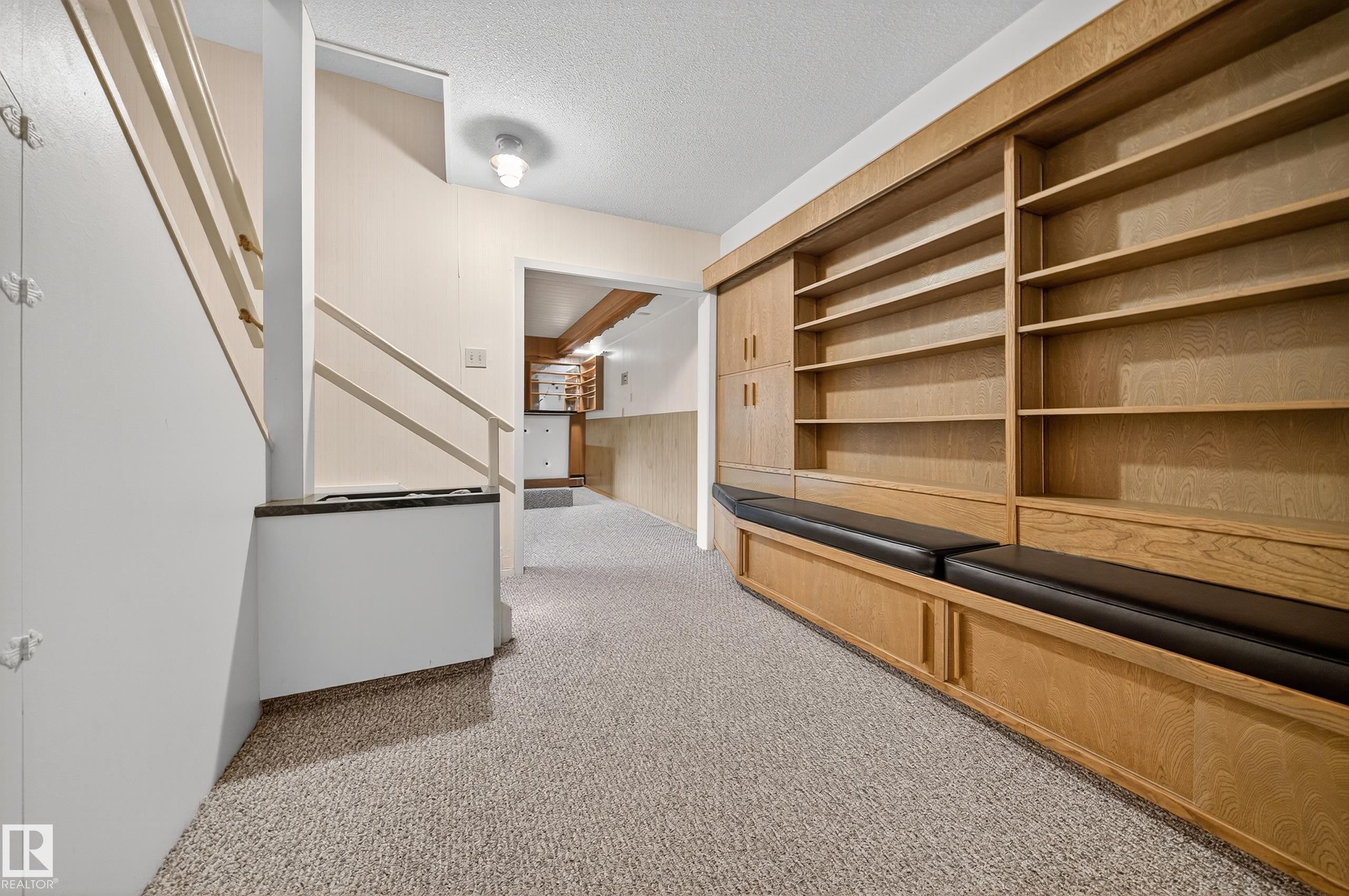 Built-in shelving with integrated bench seating and storage cabinetry, light-toned carpeting, and a staircase with white painted balusters - 707 65 Avenue, Edmonton, AB