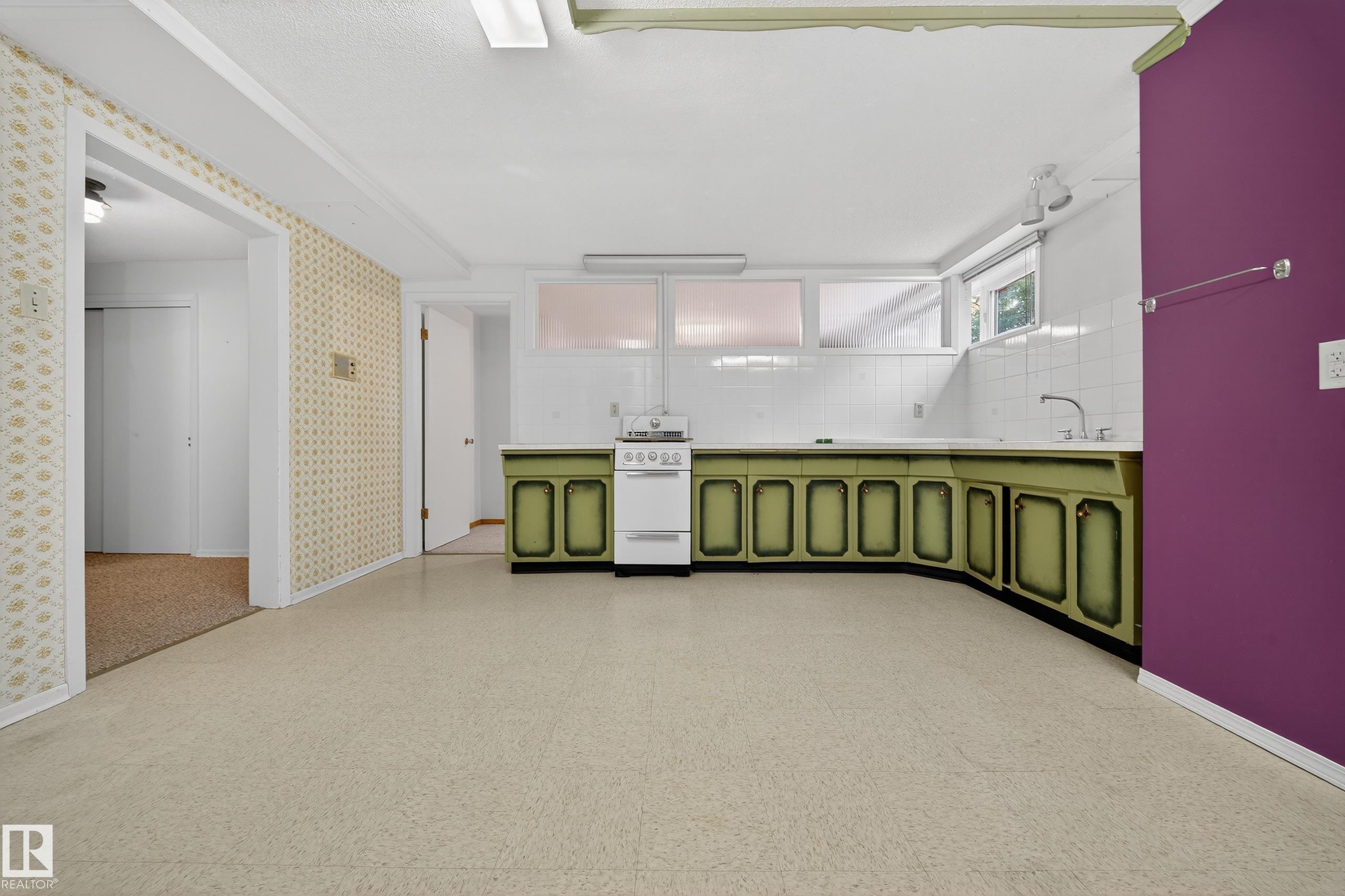 Spacious kitchen area featuring an integrated white stove, a double-basin sink, and ample counter space with built-in cabinetry - 707 65 Avenue, Edmonton, AB