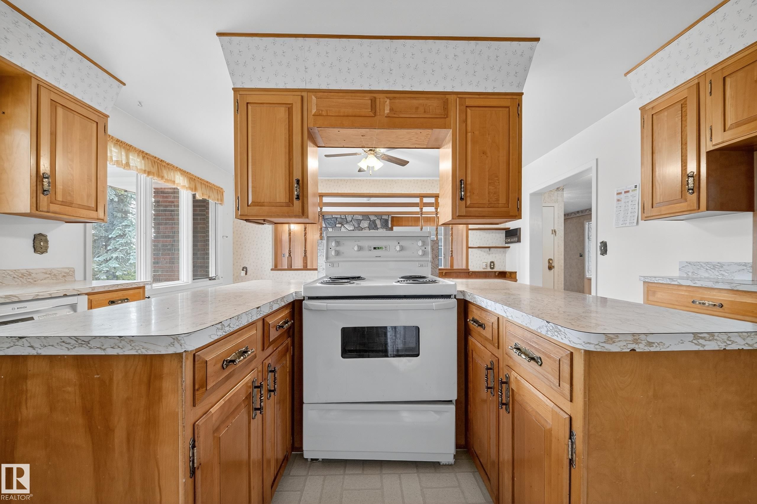 Kitchen featuring an electric range, wood cabinetry, light countertops, and a window - 707 65 Avenue, Edmonton, AB