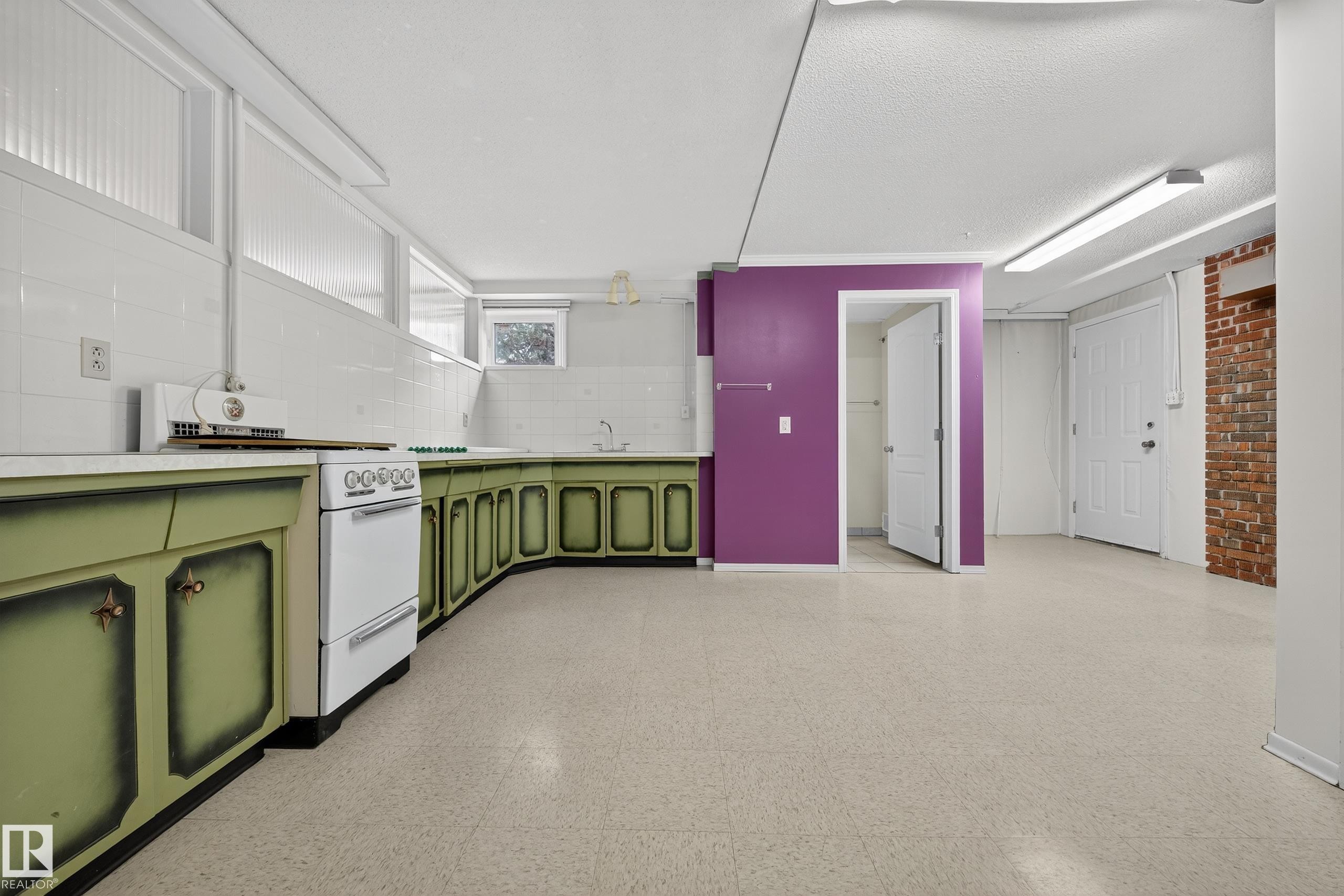 Spacious multi-purpose room featuring extensive green cabinetry, a white countertop, and white tile backsplash - 707 65 Avenue, Edmonton, AB