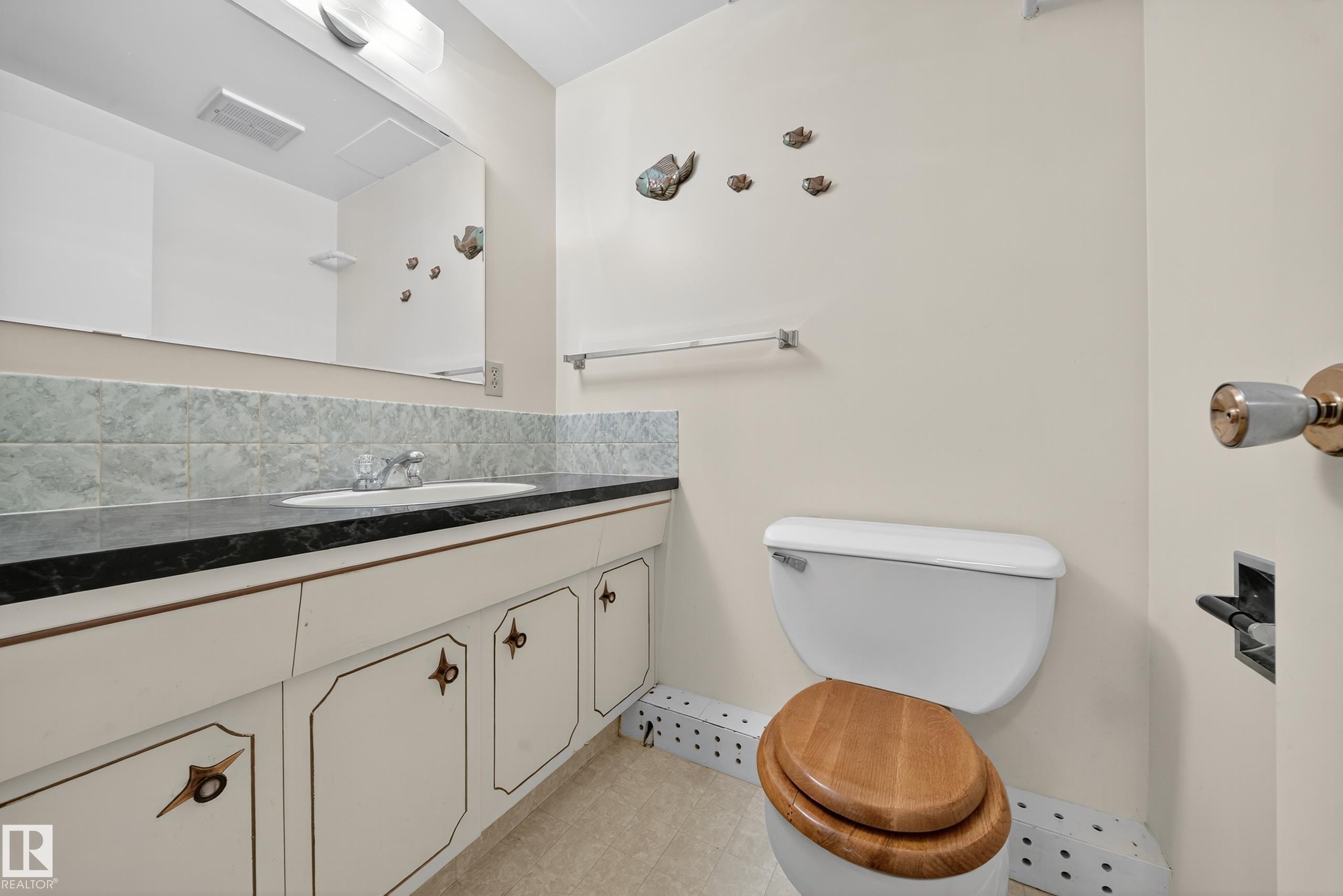 Bathroom vanity featuring a dark countertop, integrated sink, and white cabinetry - 707 65 Avenue, Edmonton, AB