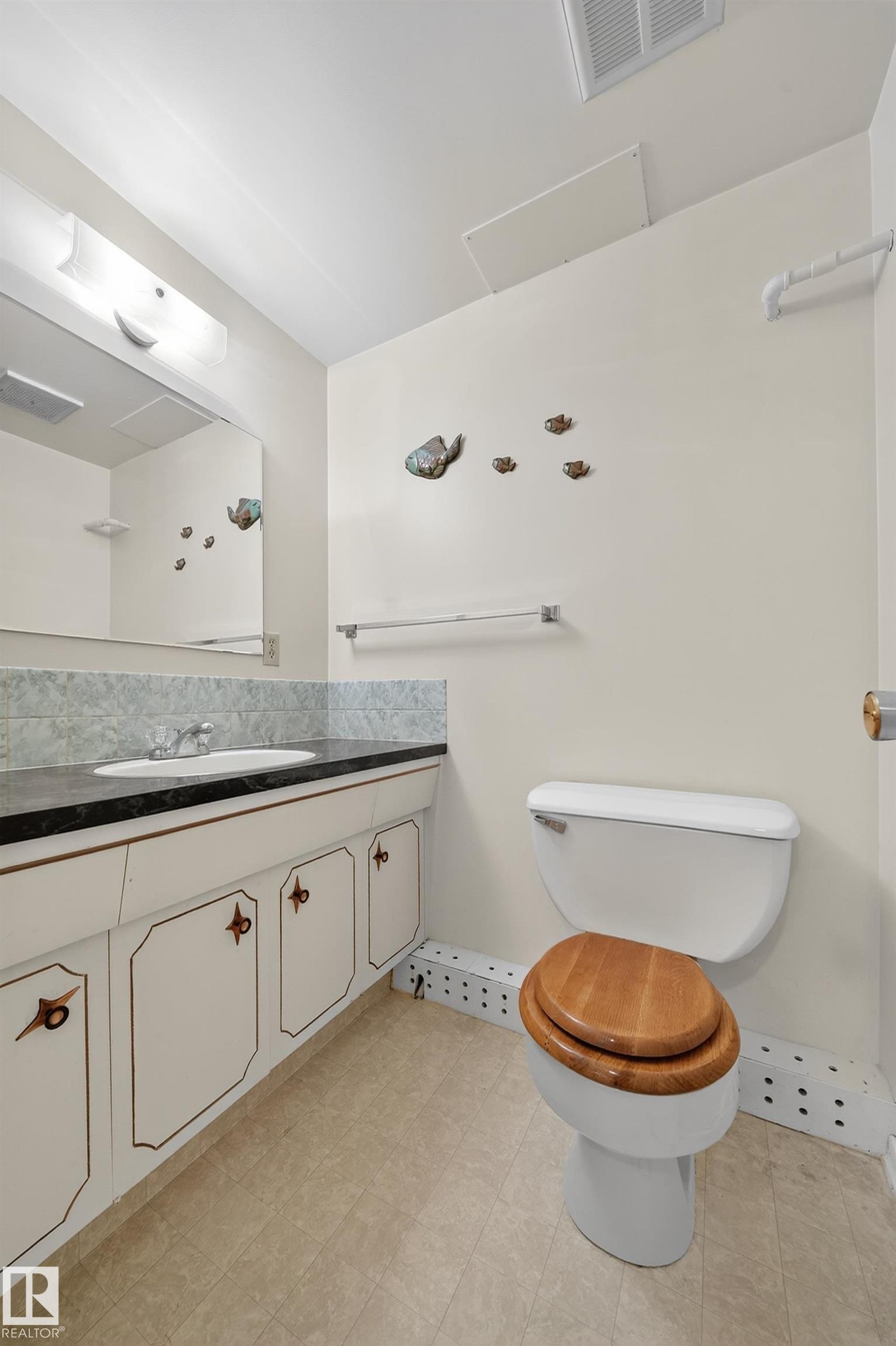 Bathroom featuring a vanity with a dark countertop, an undermount sink, and a mirrored medicine cabinet - 707 65 Avenue, Edmonton, AB