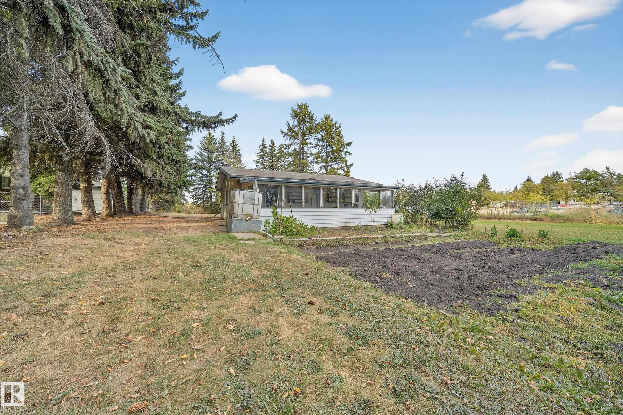 Expansive exterior featuring a screened porch, mature perimeter trees, and a prepared garden area - 707 65 Avenue, Edmonton, AB