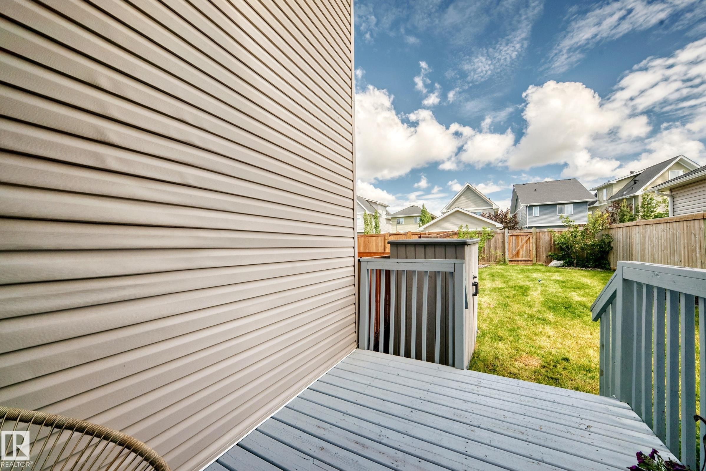 Expansive backyard featuring a manicured lawn, painted wooden deck, and full privacy fencing - 2433 Glenridding Boulevard, Edmonton, AB