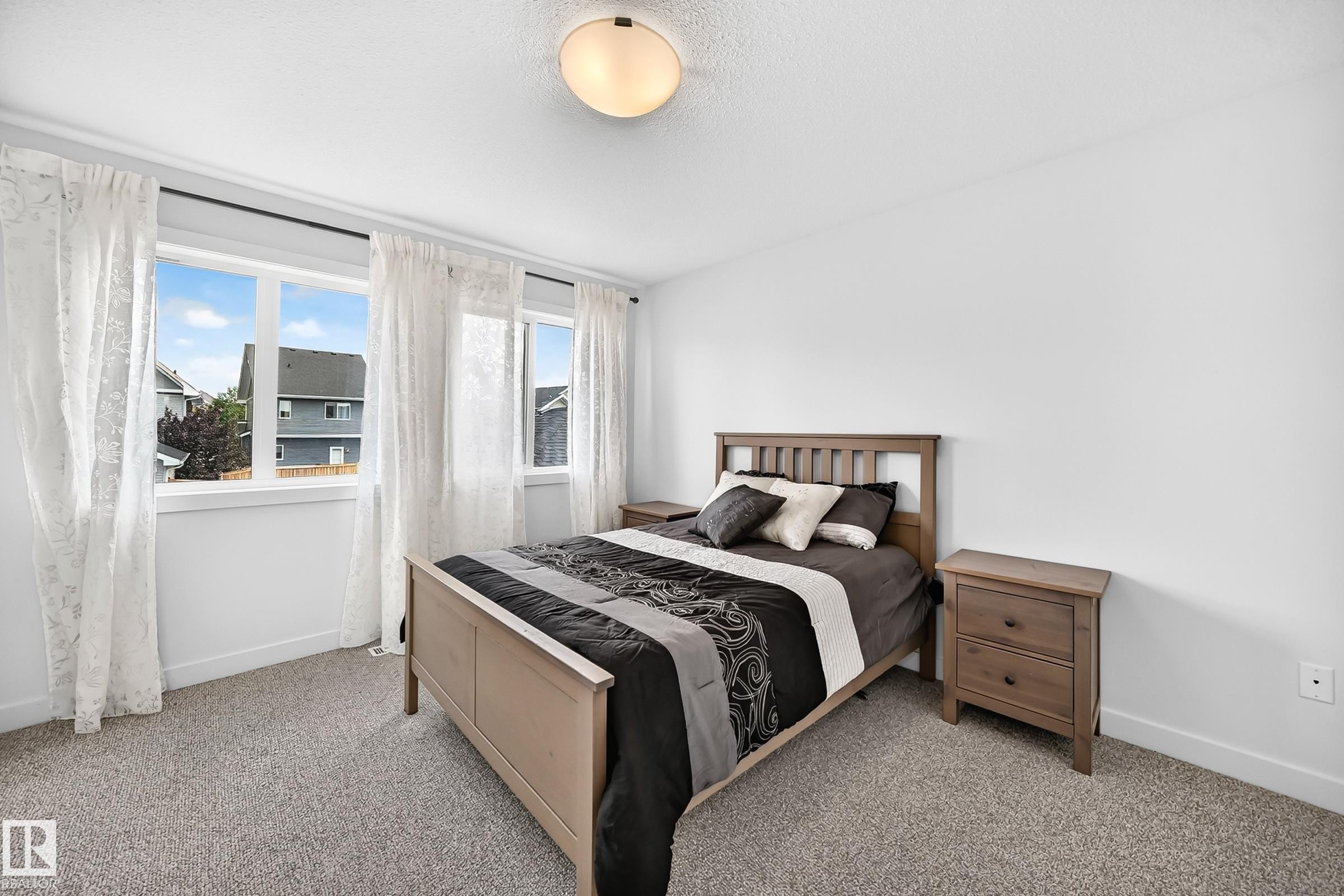 Bright room featuring a multi-pane window with white trim, a flush-mount ceiling light fixture, neutral-toned carpet flooring, and white painted walls - 2433 Glenridding Boulevard, Edmonton, AB
