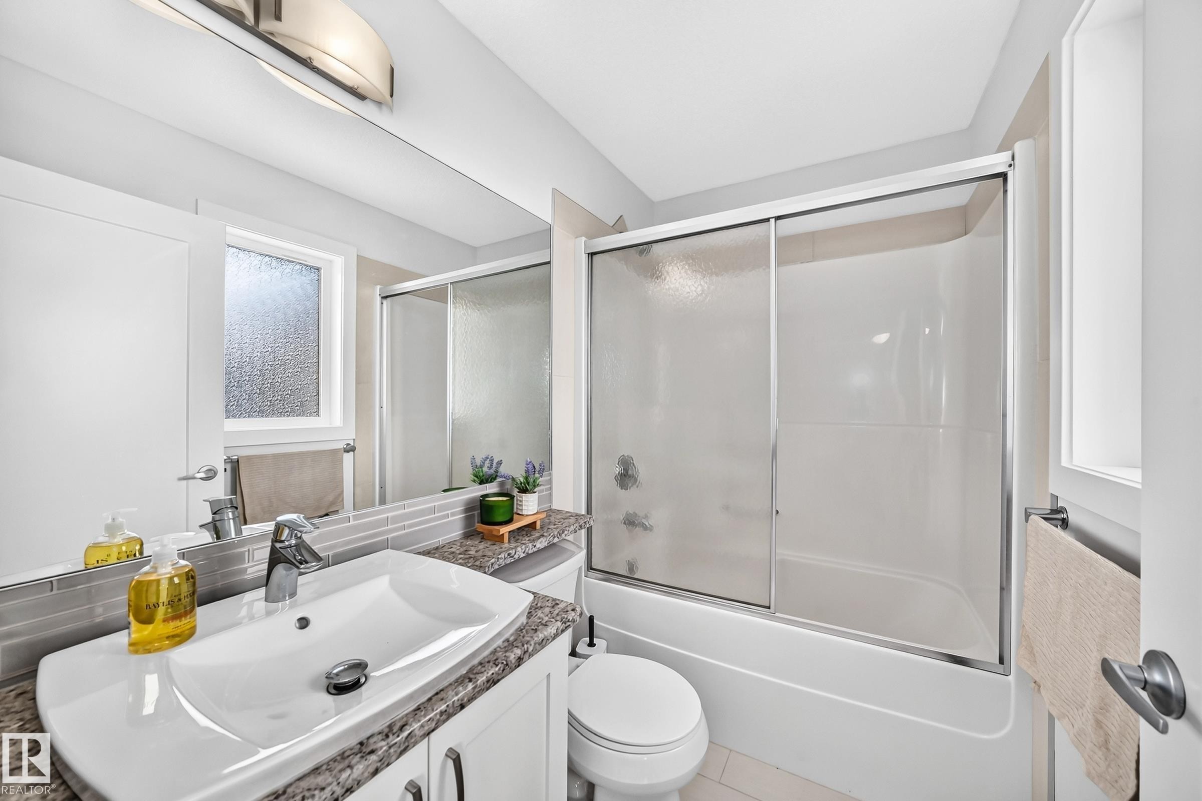 Bathroom featuring a vanity with a white vessel sink, a granite-finish countertop, and a full-width mirror - 2433 Glenridding Boulevard, Edmonton, AB