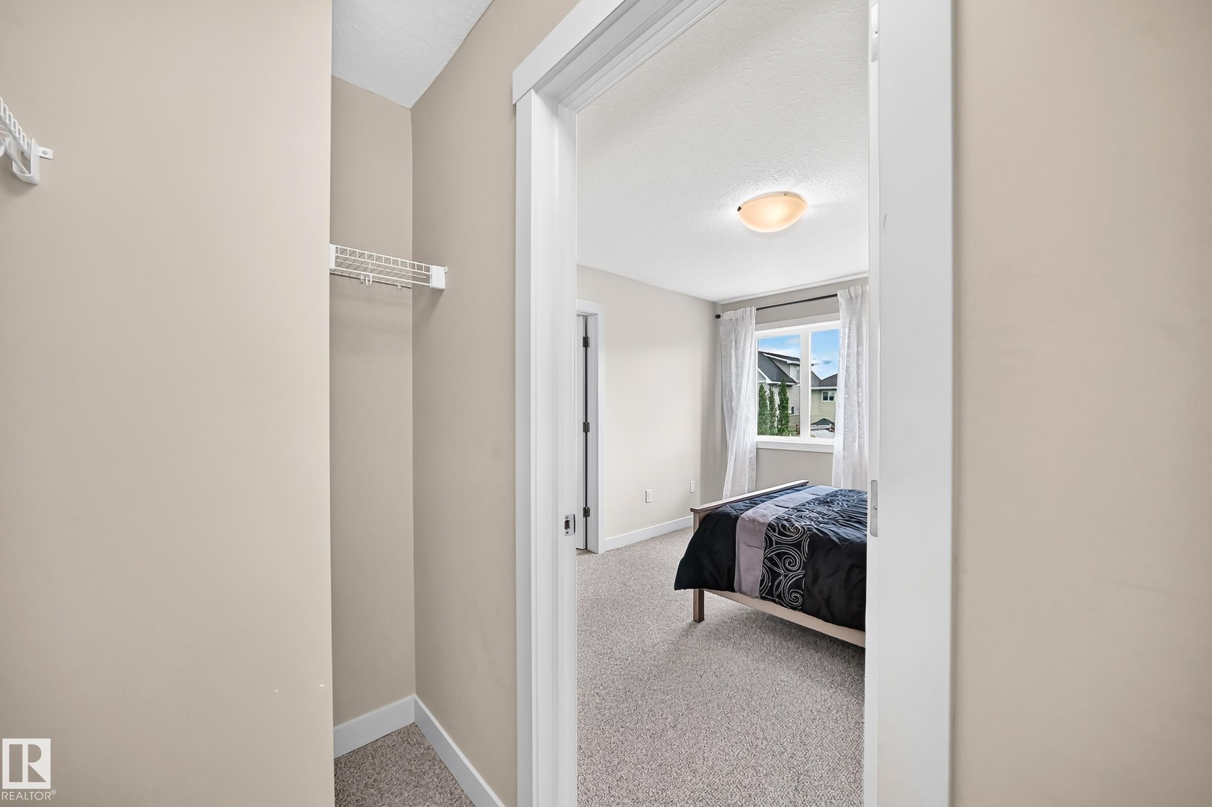 Neutral-toned bedroom with textured carpeting and a prominent window - 2433 Glenridding Boulevard, Edmonton, AB