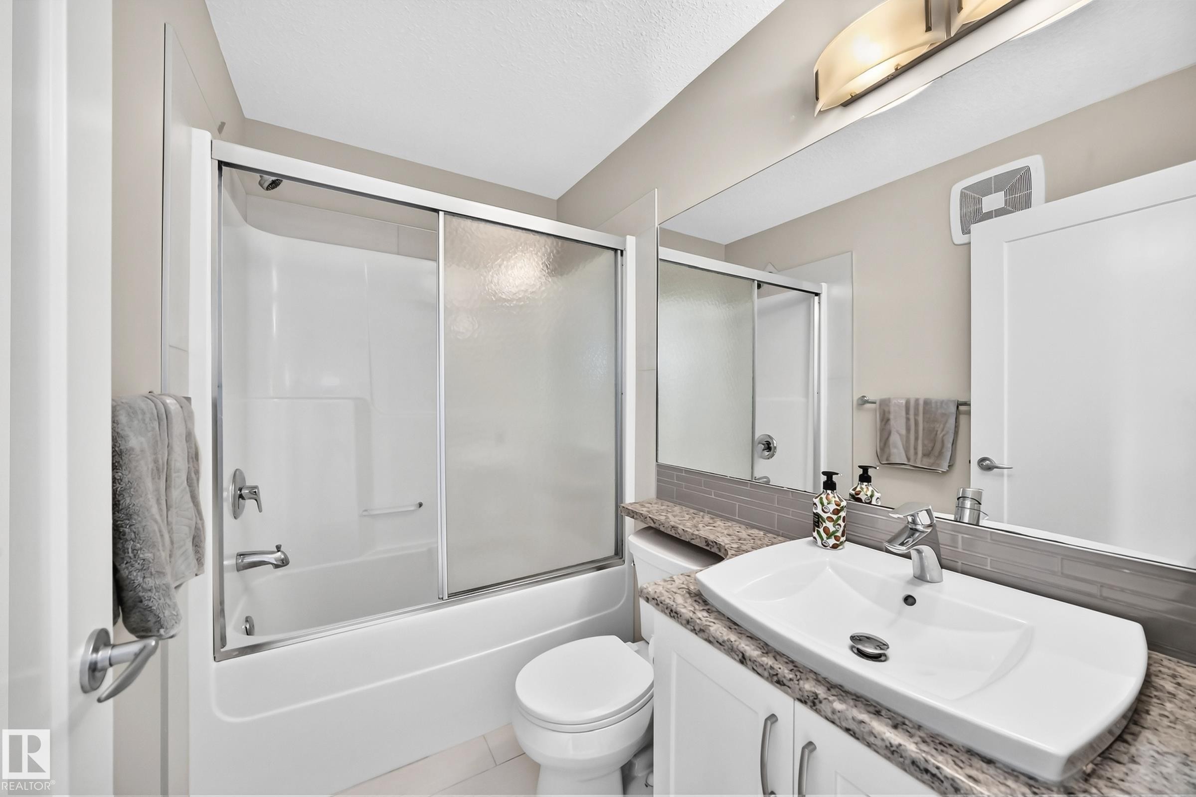 Bathroom featuring a white vanity with a granite-look countertop, an integrated vessel sink, and a chrome faucet - 2433 Glenridding Boulevard, Edmonton, AB