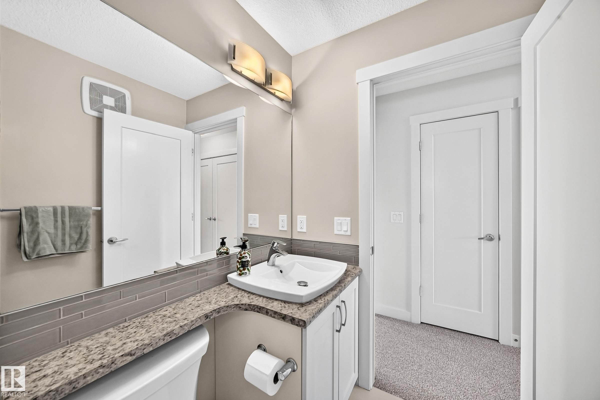 Contemporary bathroom featuring a large vanity mirror, three-light fixture, and a single vanity with a white rectangular vessel sink - 2433 Glenridding Boulevard, Edmonton, AB