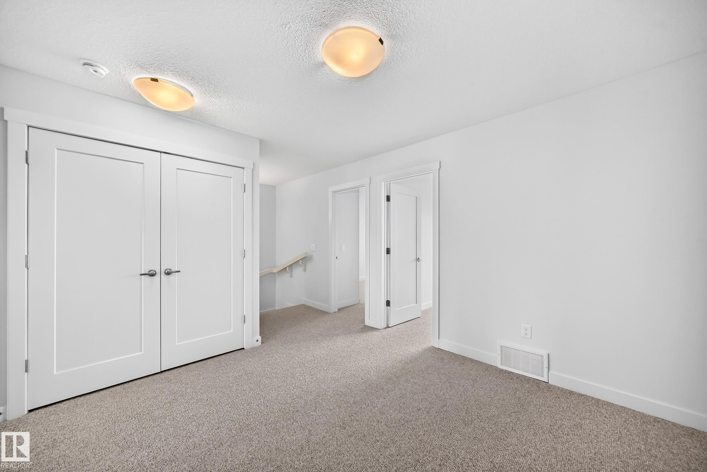 Open space featuring wall-to-wall carpeting, white interior doors with contemporary hardware, and overhead flush-mount lighting fixtures - 2433 Glenridding Boulevard, Edmonton, AB