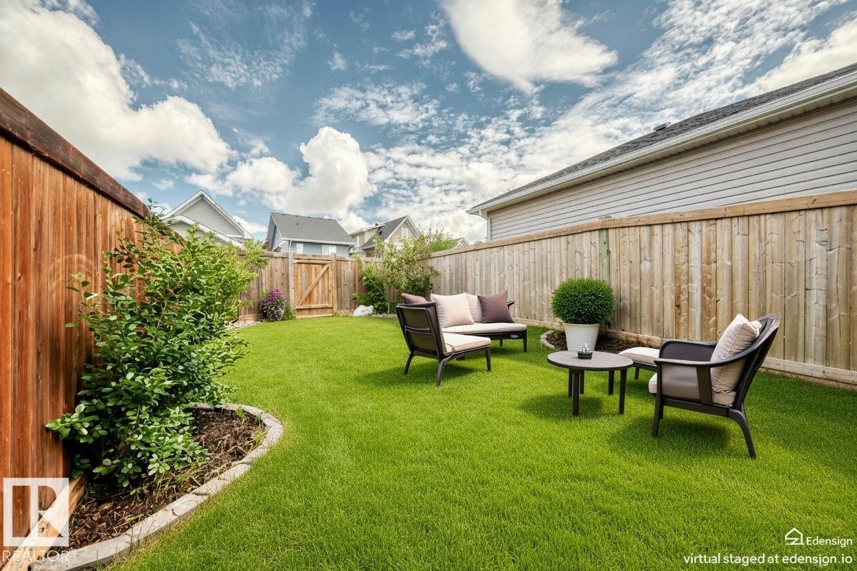 Expansive backyard featuring a green lawn, wood privacy fencing, and a decorative garden bed with established plantings - 2433 Glenridding Boulevard, Edmonton, AB