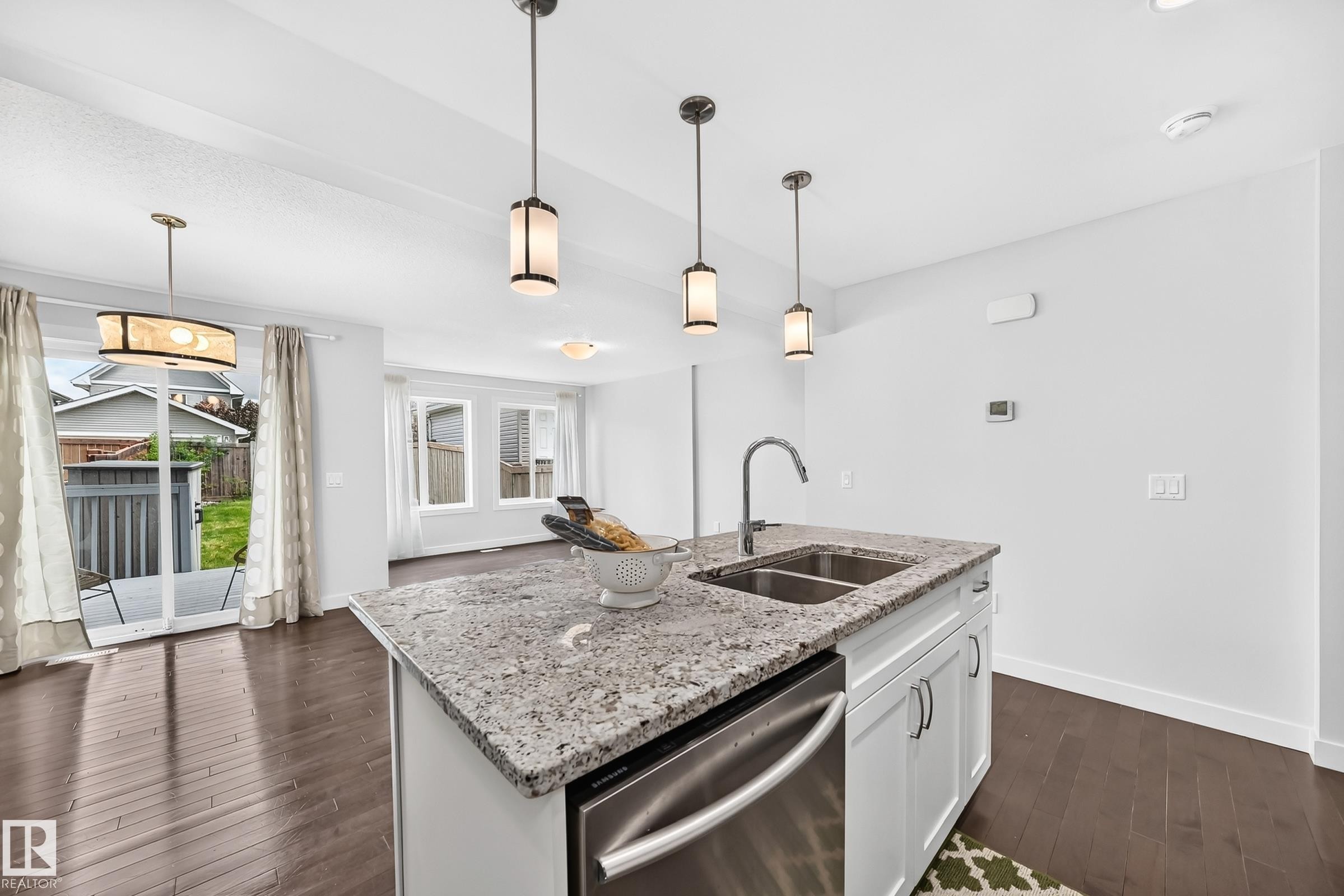 Kitchen island featuring a dual basin stainless steel sink, gooseneck faucet, and stone countertop - 2433 Glenridding Boulevard, Edmonton, AB