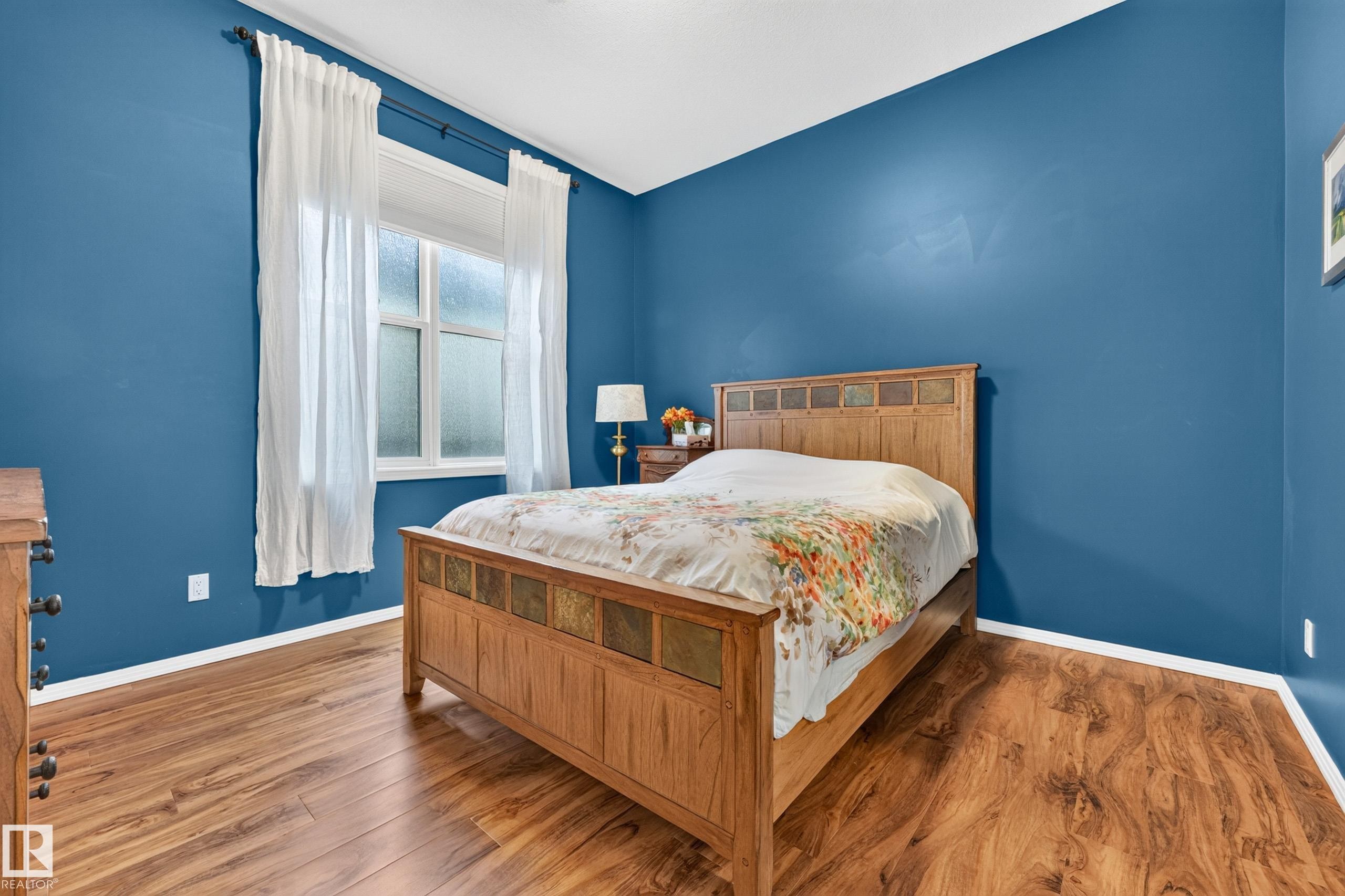 Room featuring wood-finish flooring, a window with white trim, and a white baseboard - #410 10531 117 St Nw, Edmonton, AB
