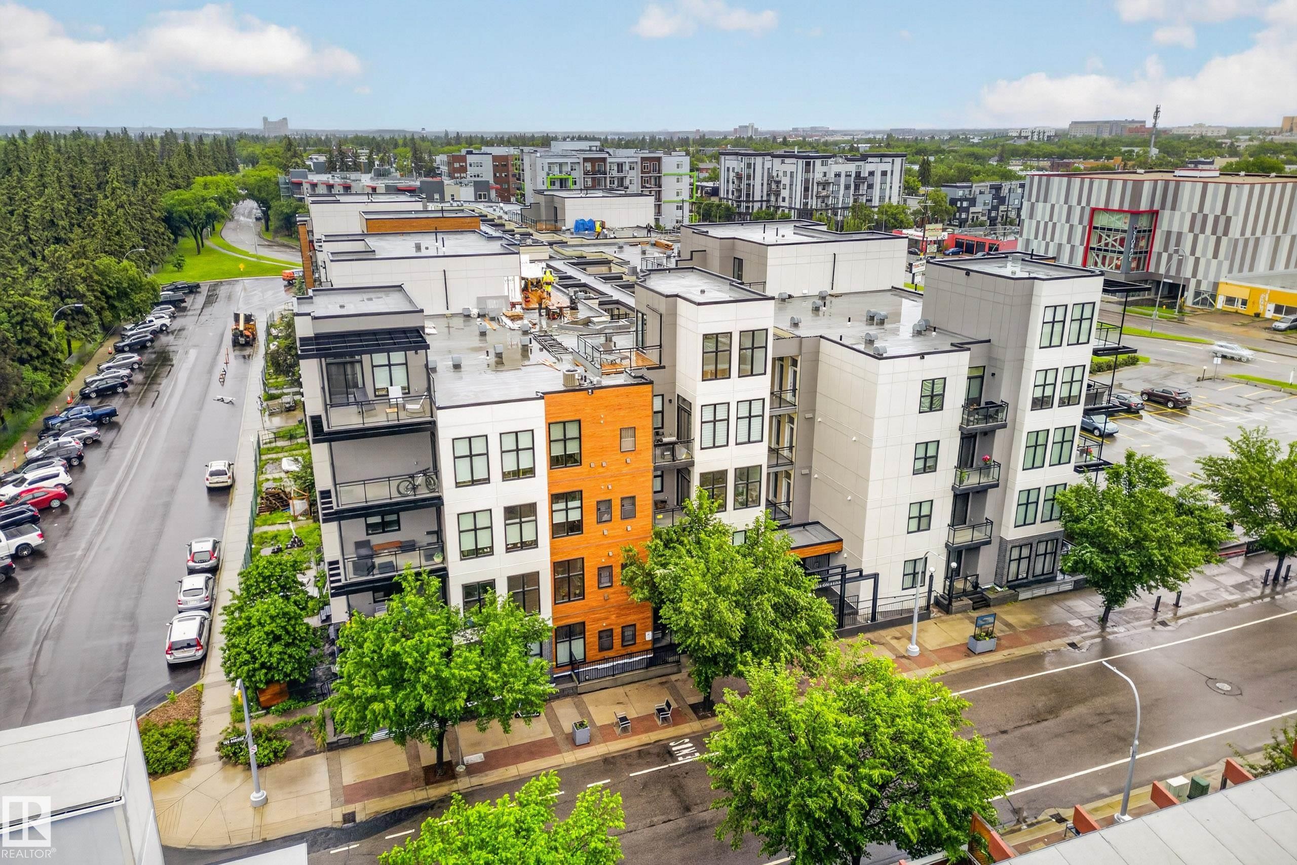 Modern multi-story building featuring varied facade materials including white panels and orange brick - #410 10531 117 St Nw, Edmonton, AB