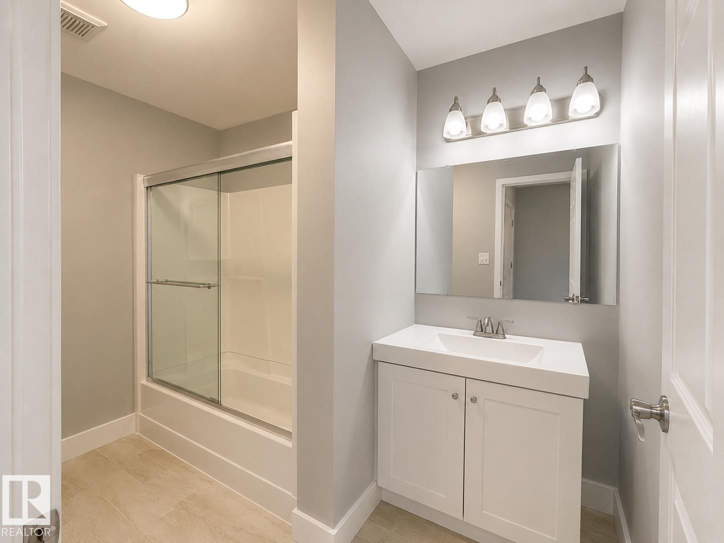 Bathroom featuring a single vanity with storage, a rectangular sink, and a framed mirror - 6348 180St, Edmonton, AB
