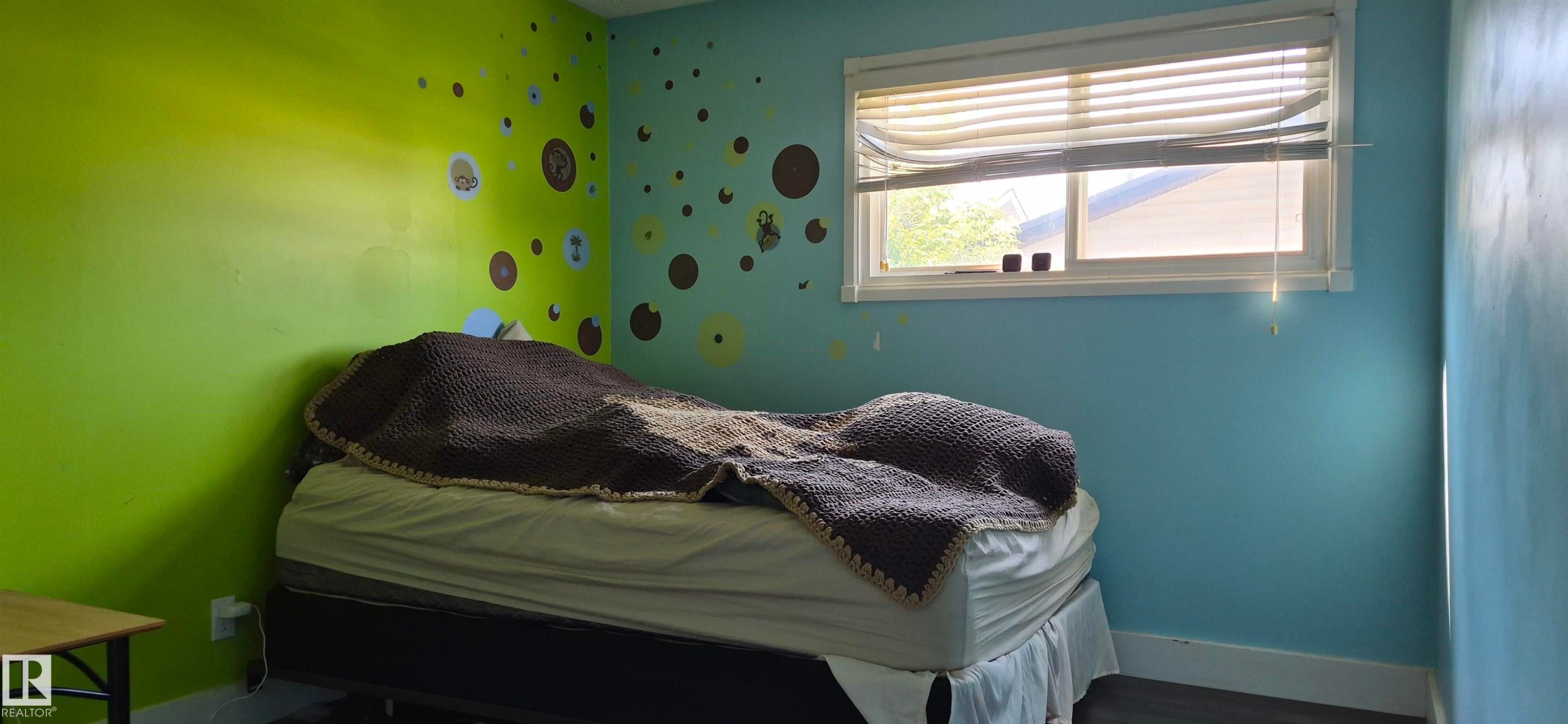 Bedroom featuring a window with horizontal blinds, providing natural illumination - 10523 105 Street, Westlock, AB