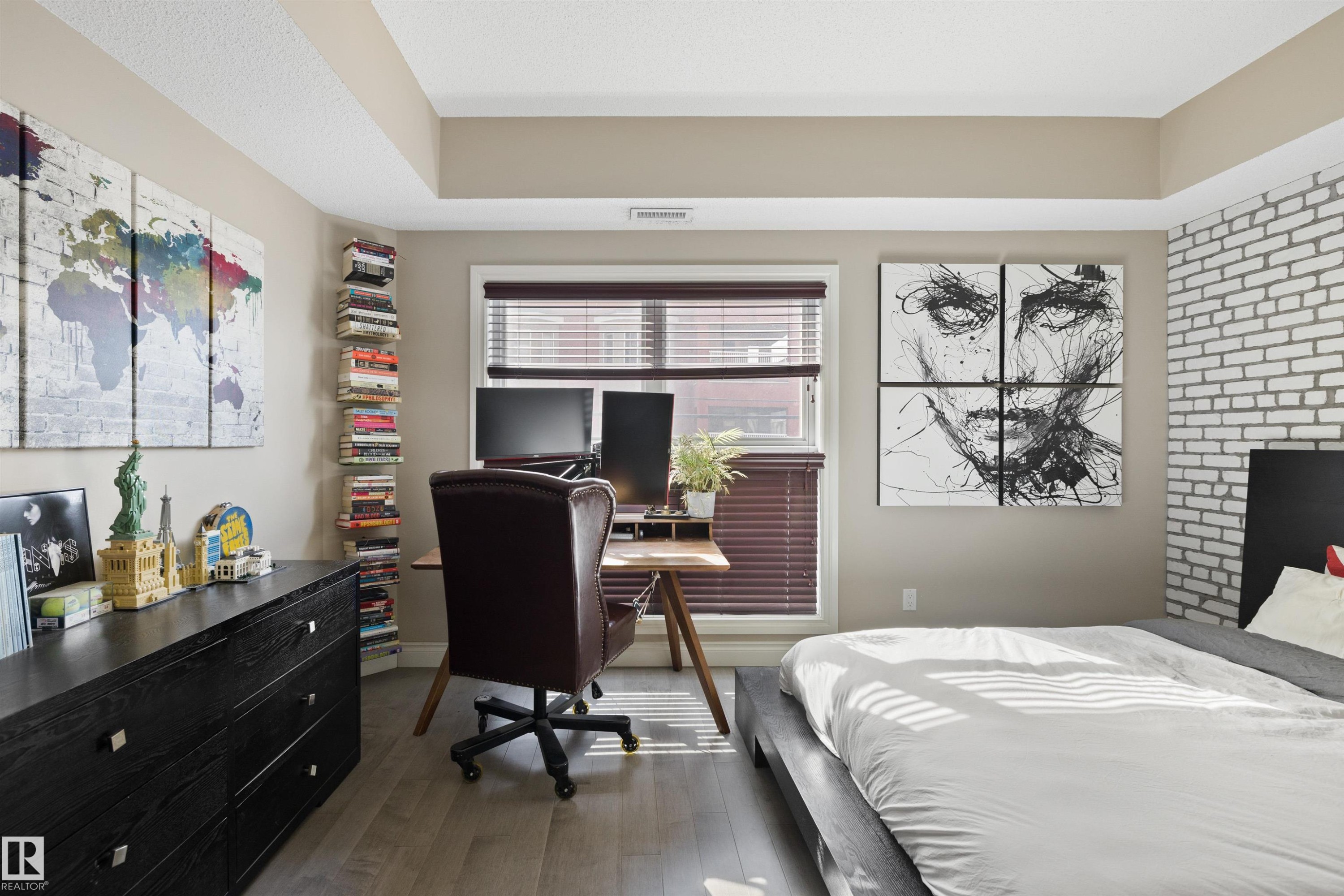 Bedroom featuring wood-finish flooring, a tray ceiling, and a window with blinds - #206 10232 115 St Nw, Edmonton, AB