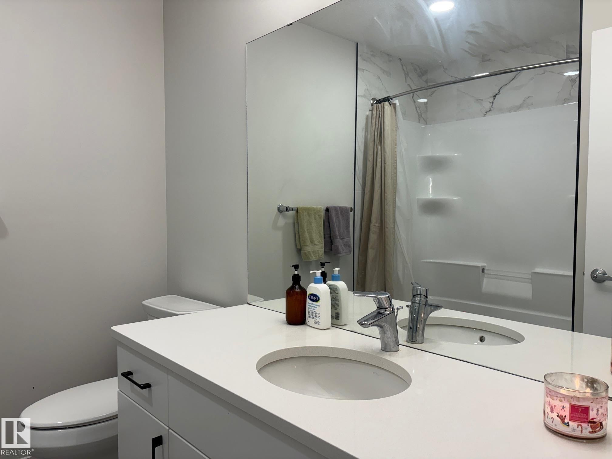 Bathroom featuring a white vanity with integrated sink, chrome faucet, and black hardware - 9952 227 Street, Edmonton, AB