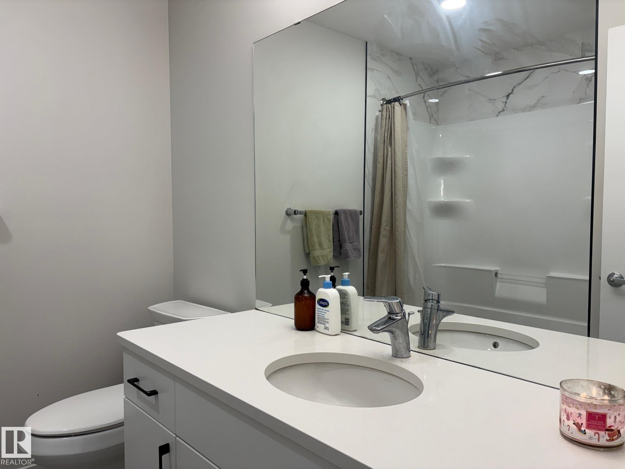 Bathroom featuring a white vanity with an integrated sink, polished chrome faucet, and a large wall-mounted mirror - 9952 227 Street, Edmonton, AB