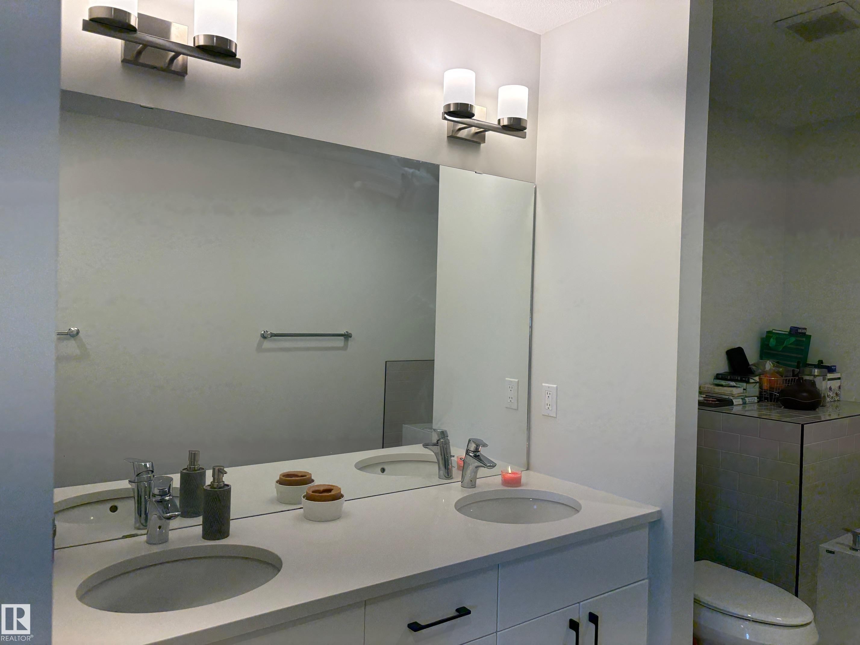 Dual vanity featuring integrated sinks, chrome faucets, and white cabinetry with matte black hardware - 9952 227 Street, Edmonton, AB