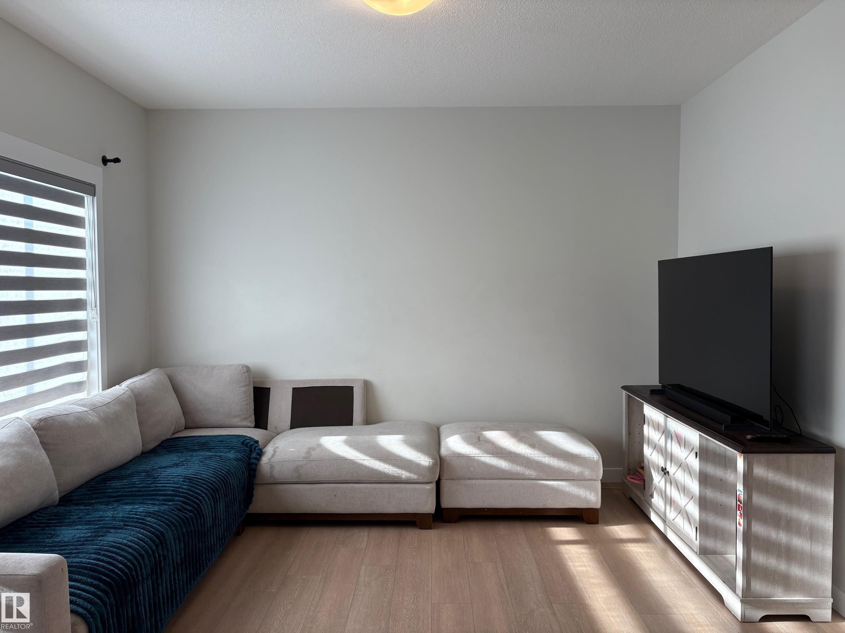 Light wood-finish flooring throughout, complemented by light gray wall paint - 9952 227 Street, Edmonton, AB