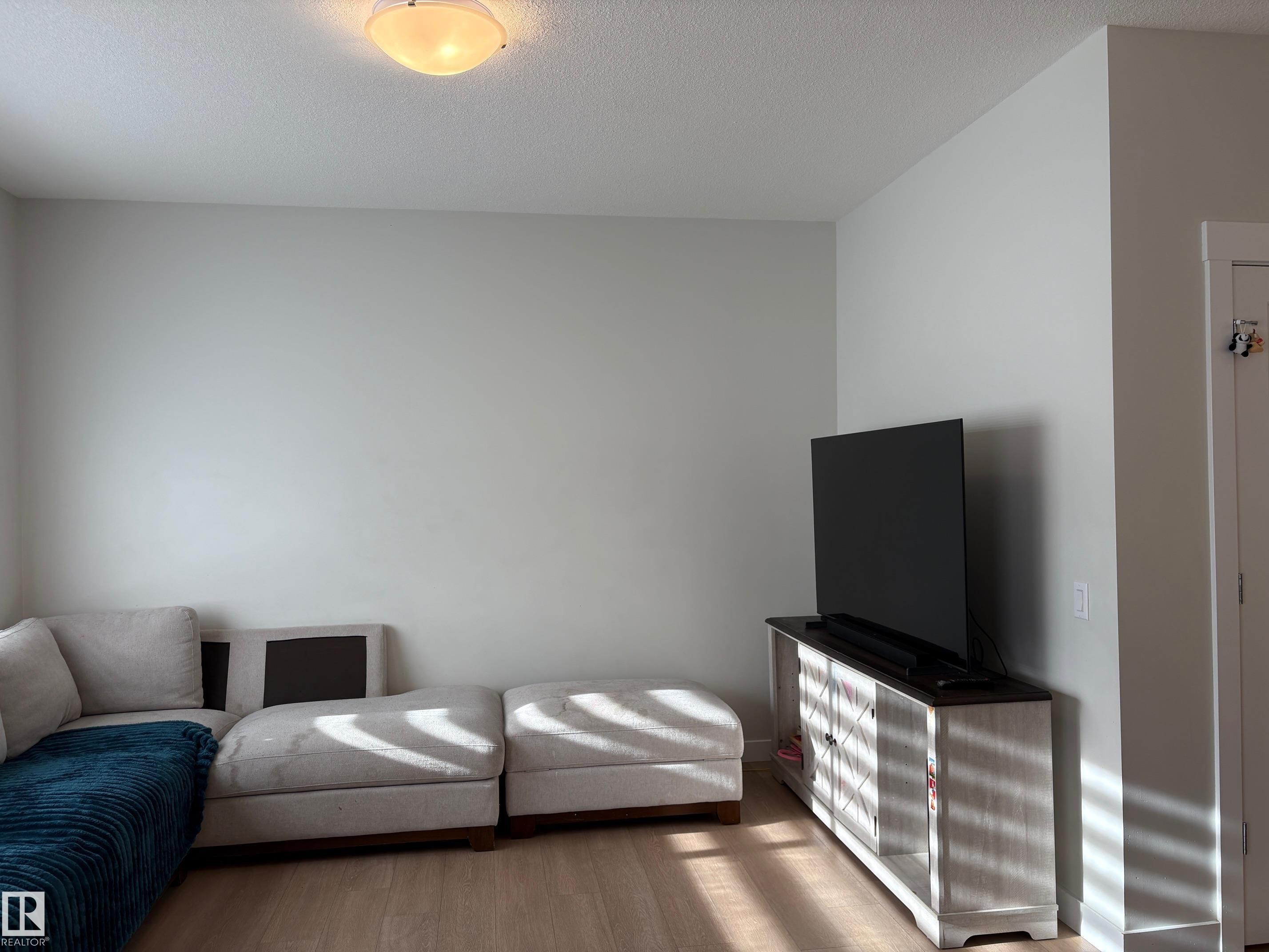 Light wood-finish flooring with neutral wall paint and a flush-mount ceiling light - 9952 227 Street, Edmonton, AB