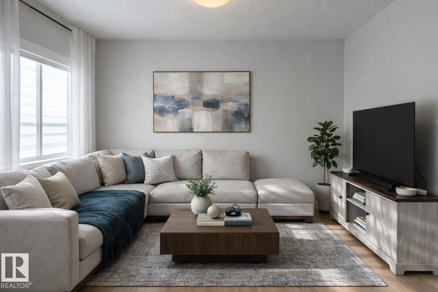Virtually staged. Living area featuring wood-finish flooring, light grey painted walls, and a large window with privacy blinds and sheer curtains - 9952 227 Street, Edmonton, AB