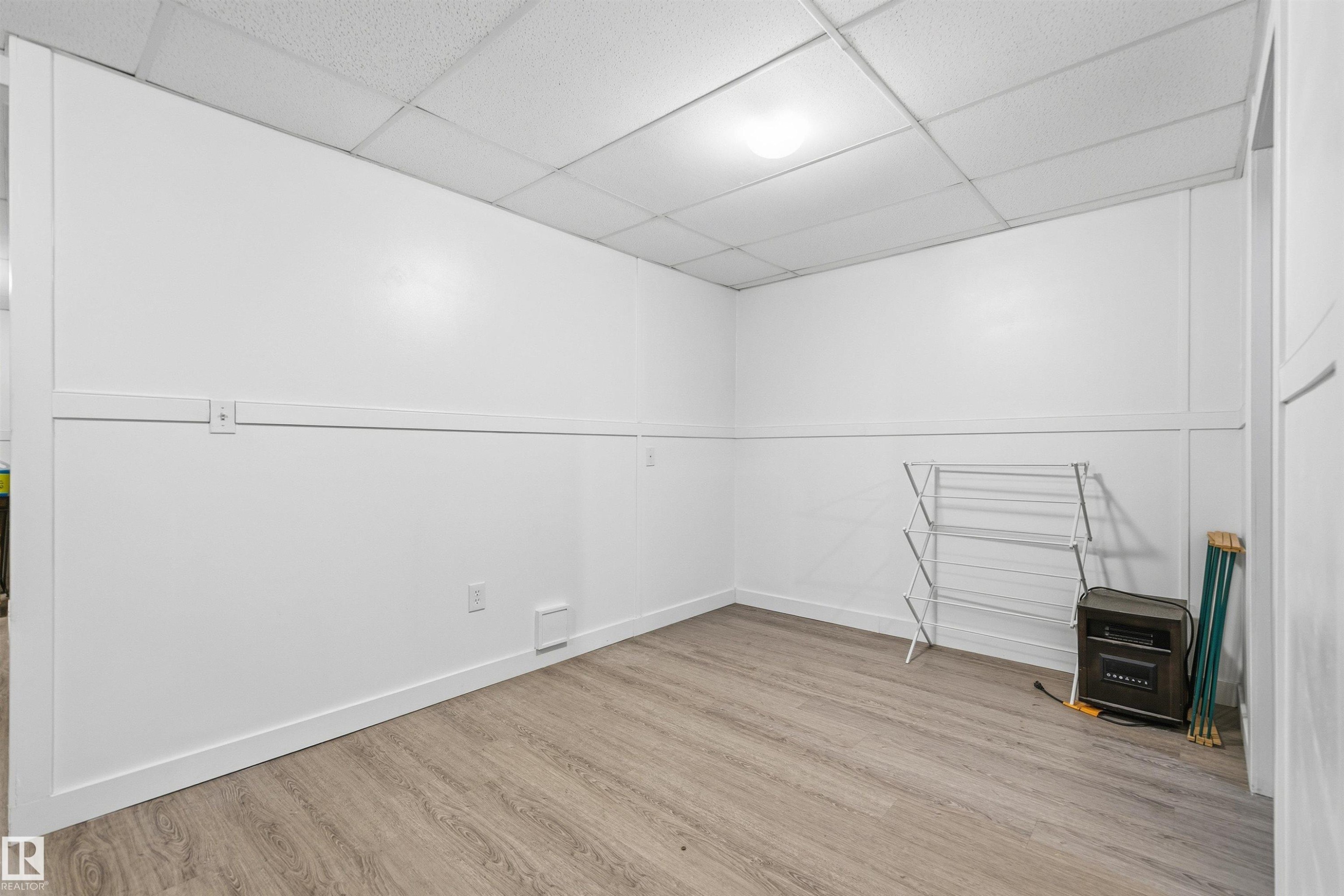Light wood-finish flooring complements crisp white walls with paneling - 21207 90Ave, Edmonton, AB