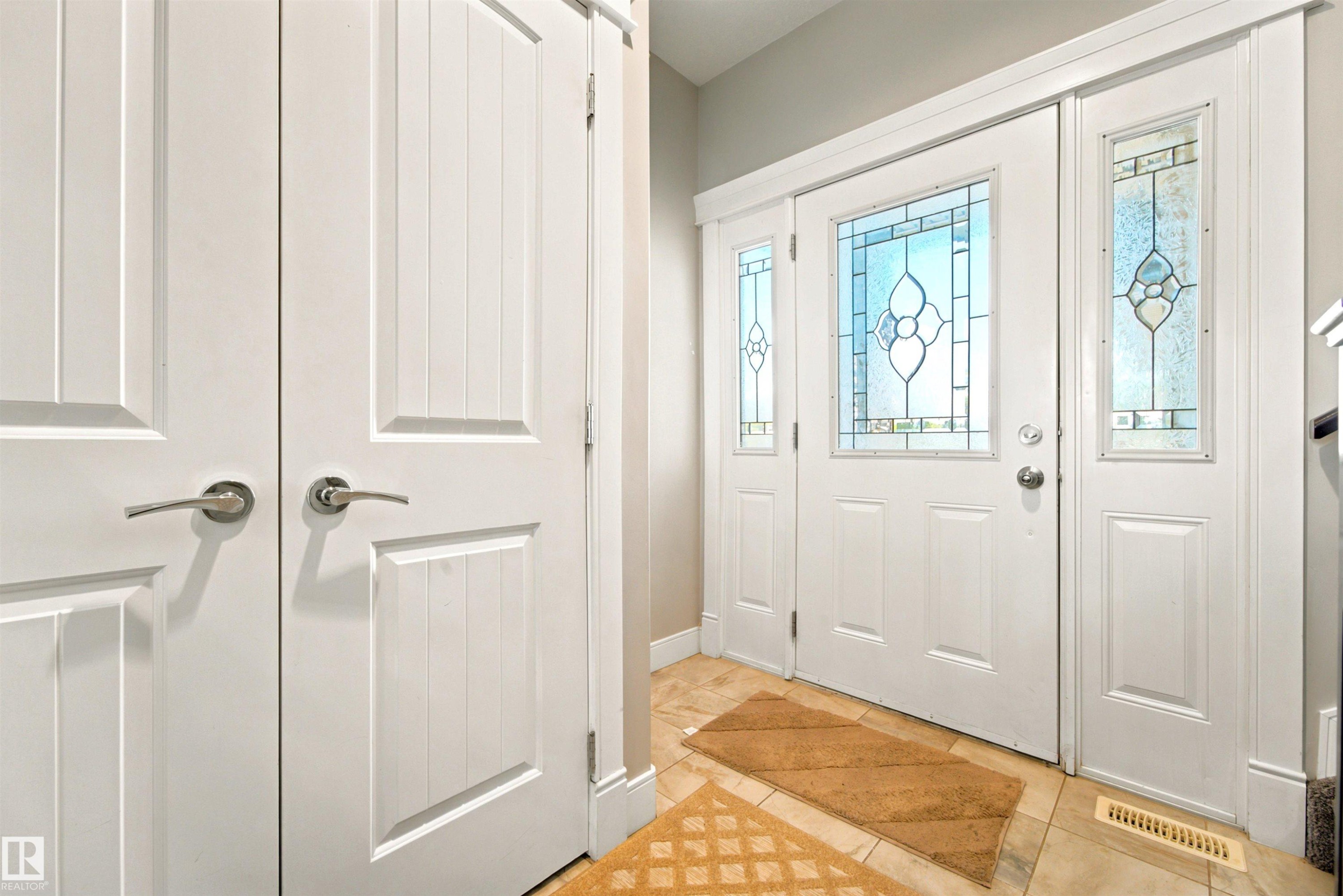 Entryway featuring a white paneled door with decorative stained glass, flanked by two matching sidelights - 5110 Rue Eaglemont, Beaumont, AB