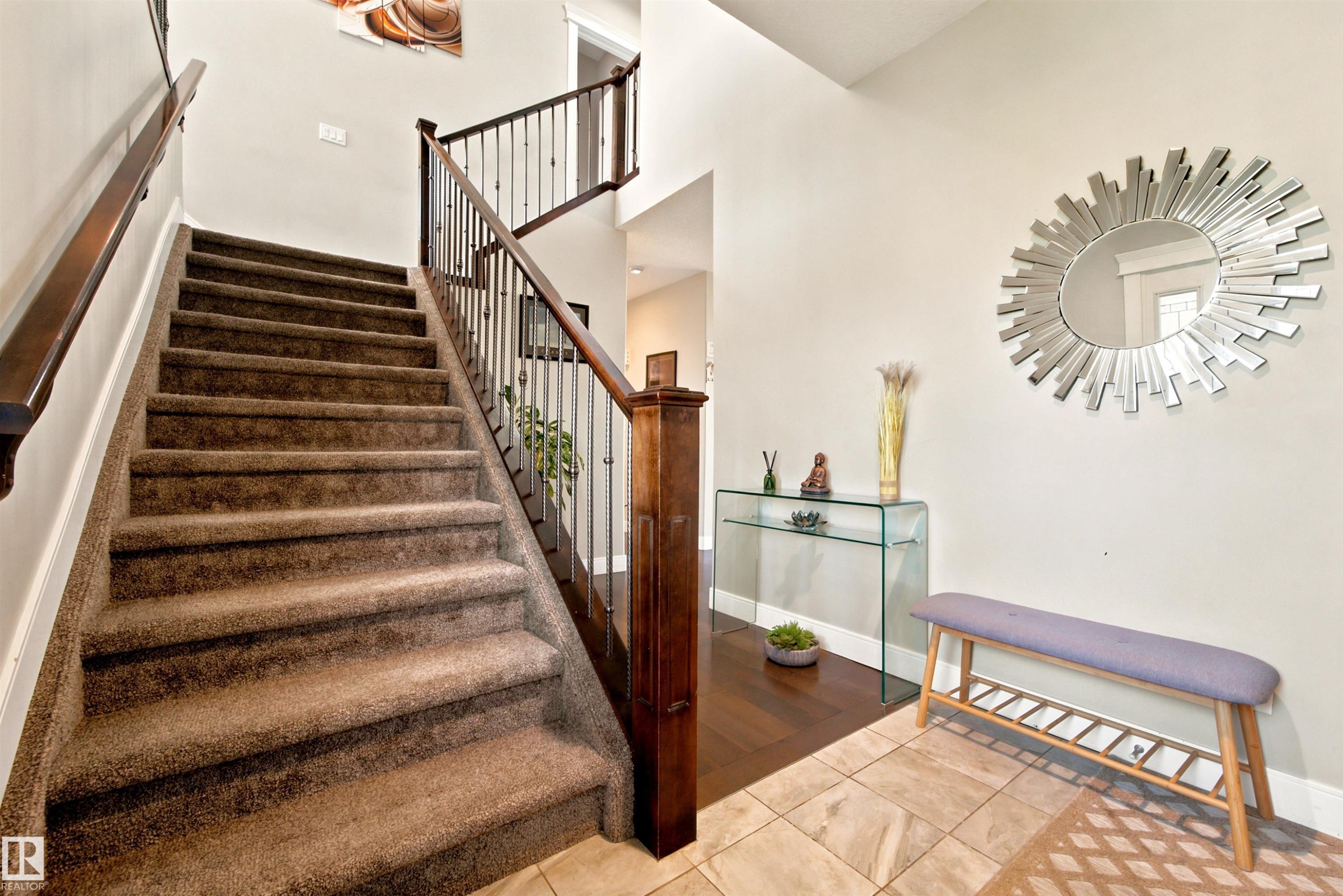 Carpeted staircase featuring dark wood newel posts and handrails with metal balusters - 5110 Rue Eaglemont, Beaumont, AB