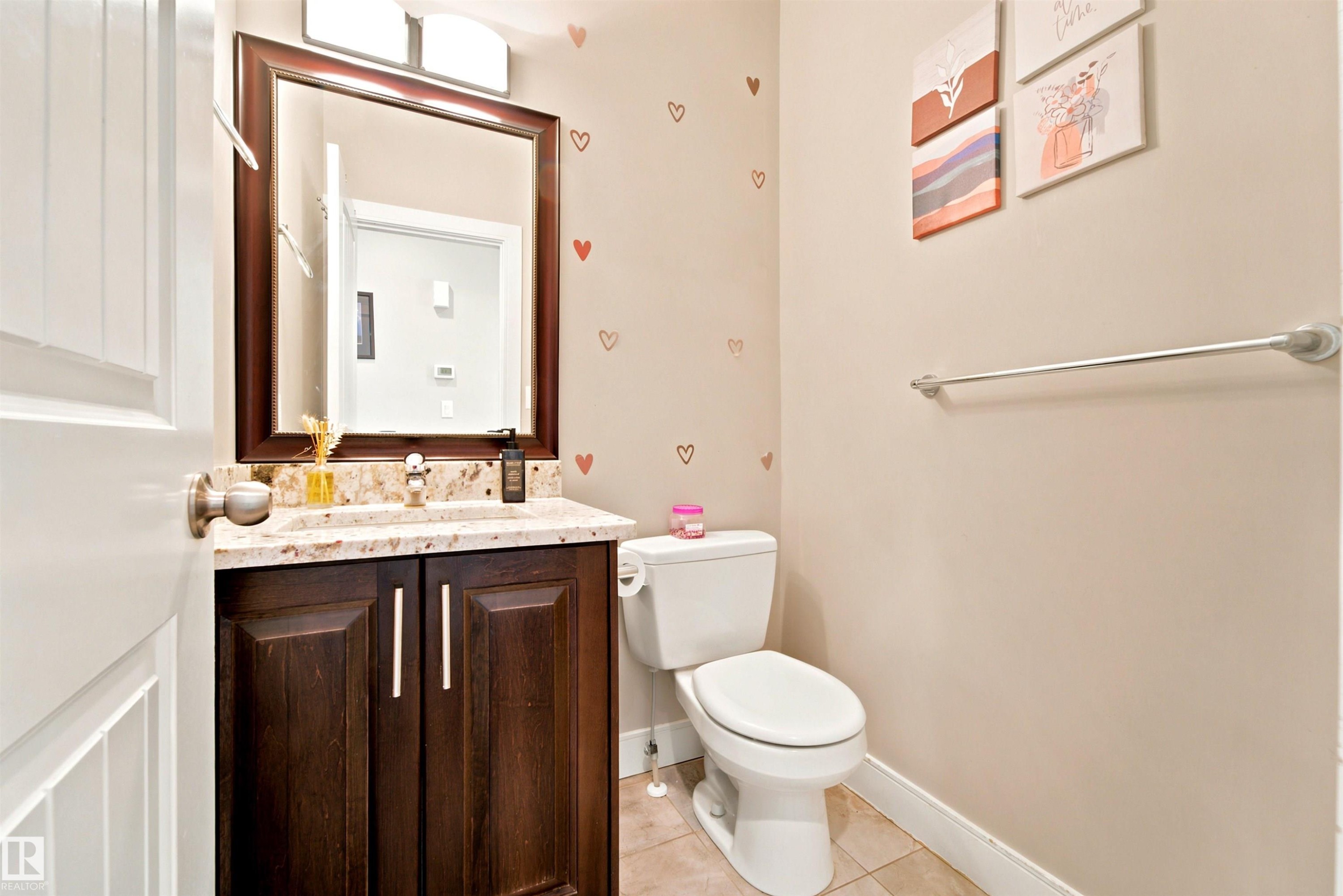 Bathroom vanity featuring a granite-style countertop, a dark wood-finish cabinet with double doors, and an undermount sink - 5110 Rue Eaglemont, Beaumont, AB