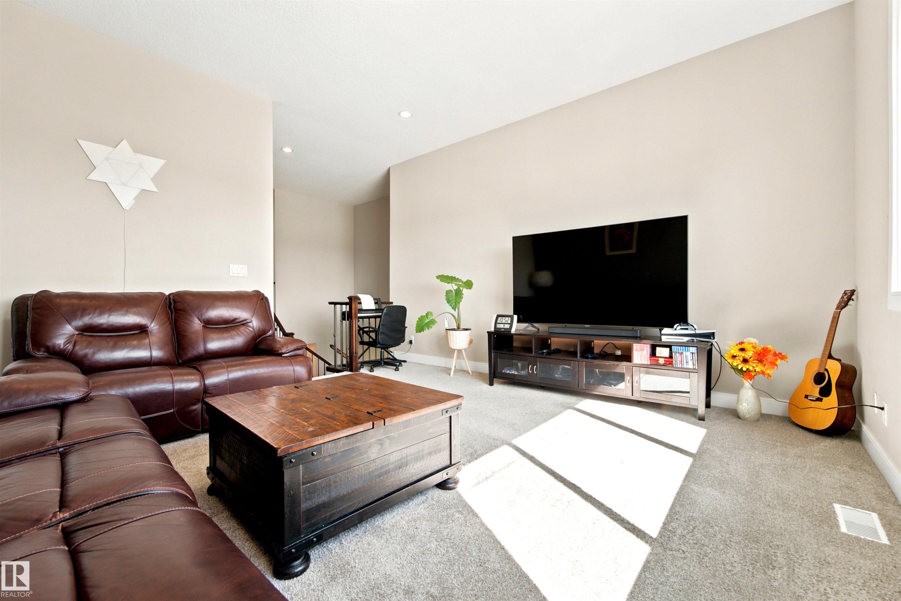 Carpeted living area featuring high ceilings, recessed lighting, and a window providing natural light - 5110 Rue Eaglemont, Beaumont, AB
