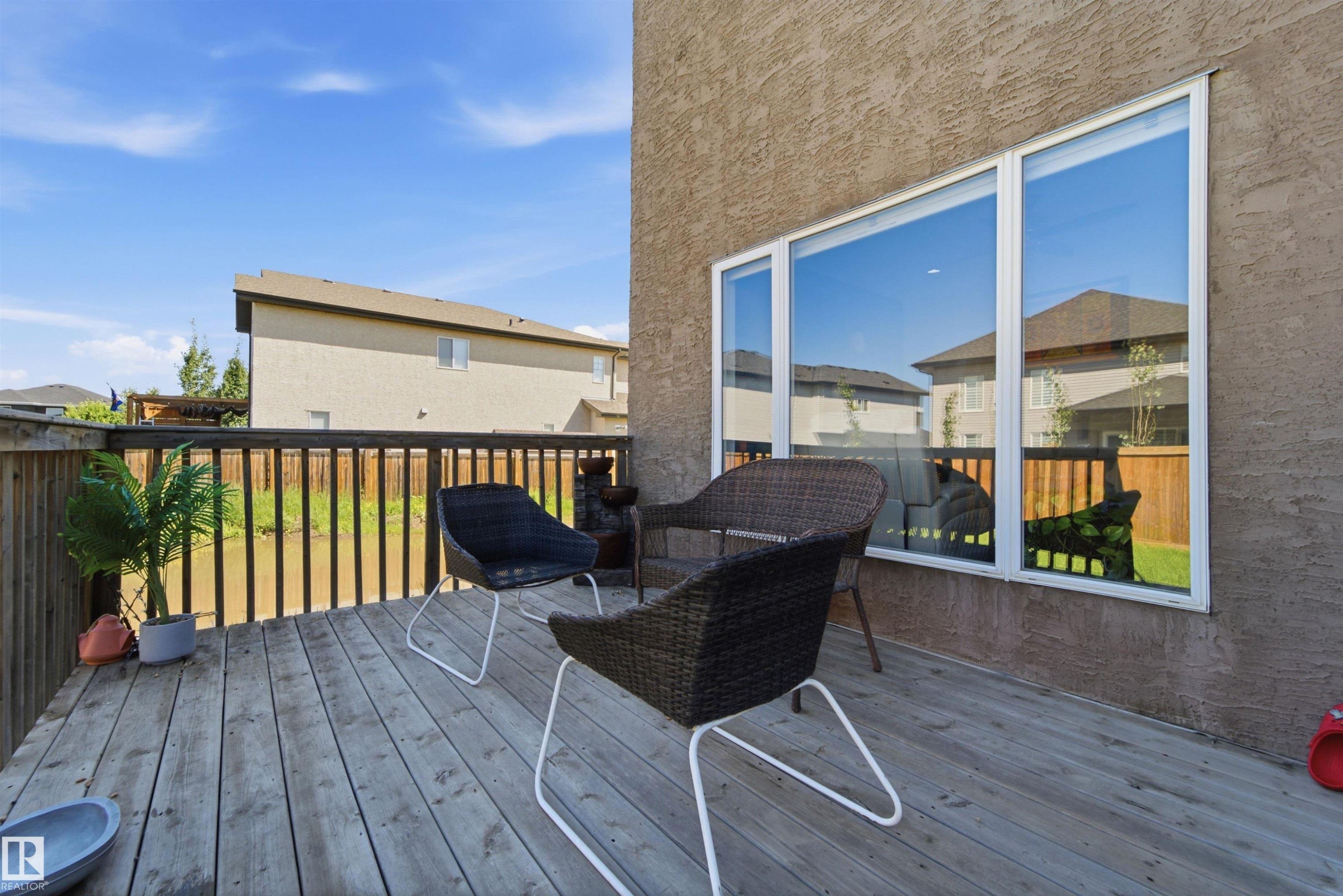 Expansive wood deck with a full wood railing overlooking a grassy area - 5110 Rue Eaglemont, Beaumont, AB