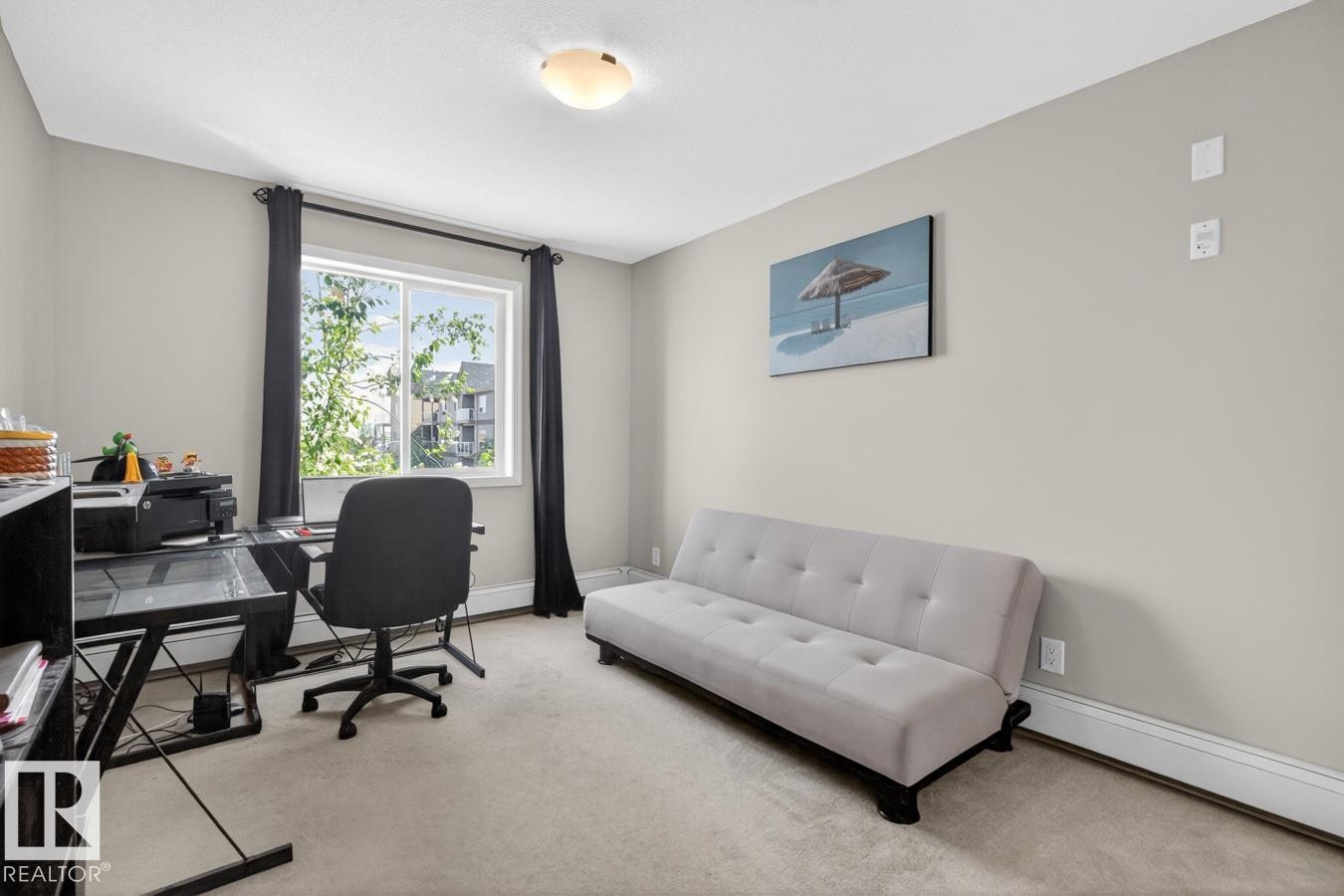Carpeted interior room featuring a large window with dark drapes, light-toned walls, and a ceiling-mounted light fixture - 320 5005 165 Avenue, Edmonton, AB - Indoor Photo Showing Office