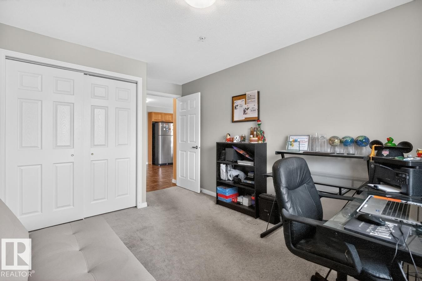 Carpeted room featuring a double bifold closet, light gray wall paint, and a standard ceiling light fixture - 320 5005 165 Avenue, Edmonton, AB - Indoor Photo Showing Office