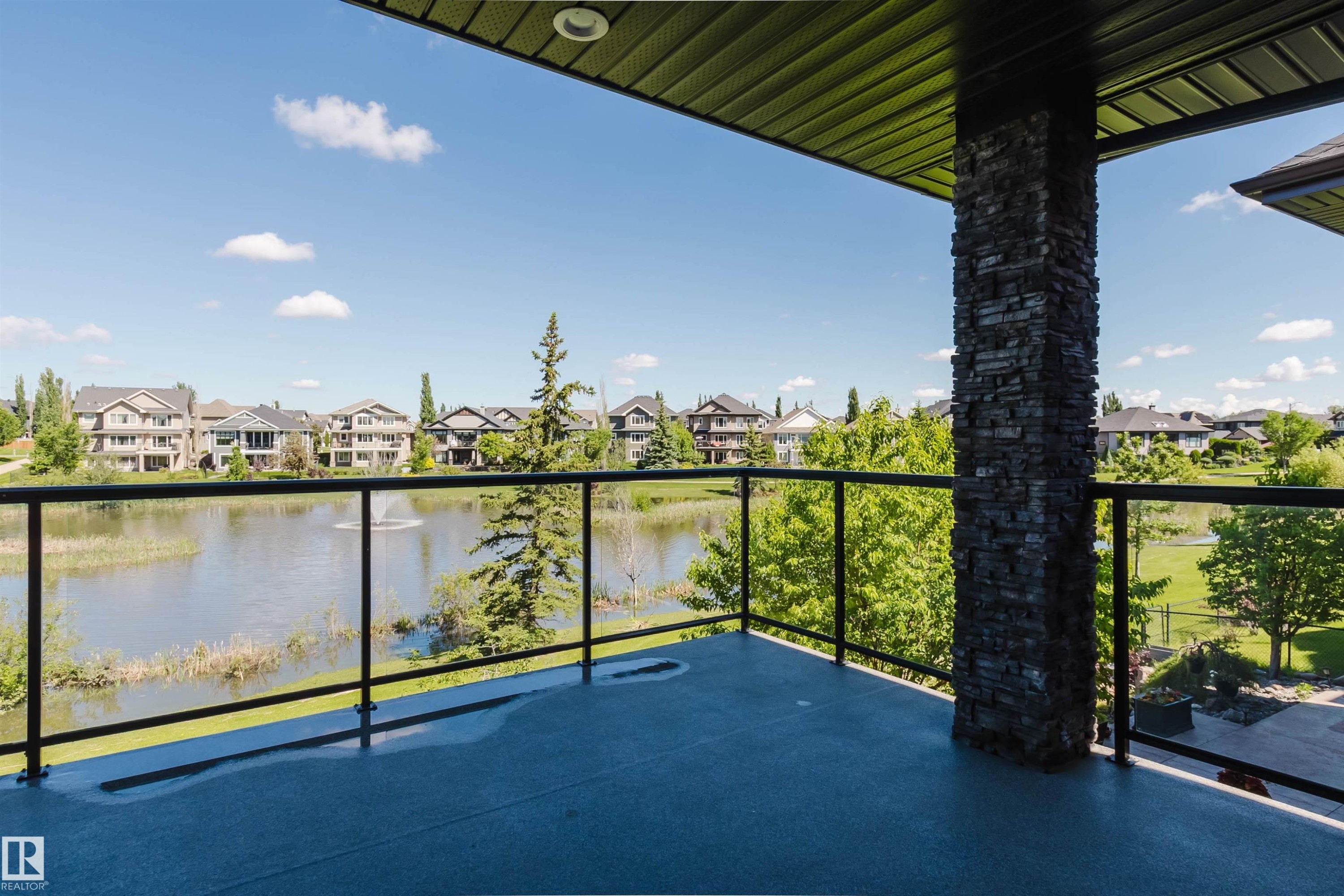 Spacious private balcony featuring glass panel railings, a stone-clad pillar, and a textured floor surface - 3438 West Landing Landing, Edmonton, AB