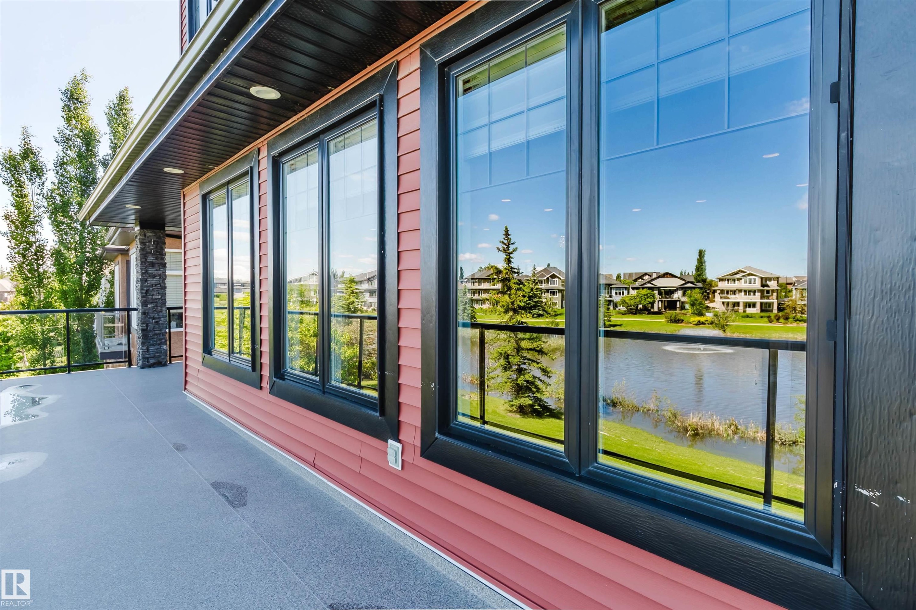 Private balcony with clear glass railing, textured flooring, and red siding - 3438 West Landing Landing, Edmonton, AB