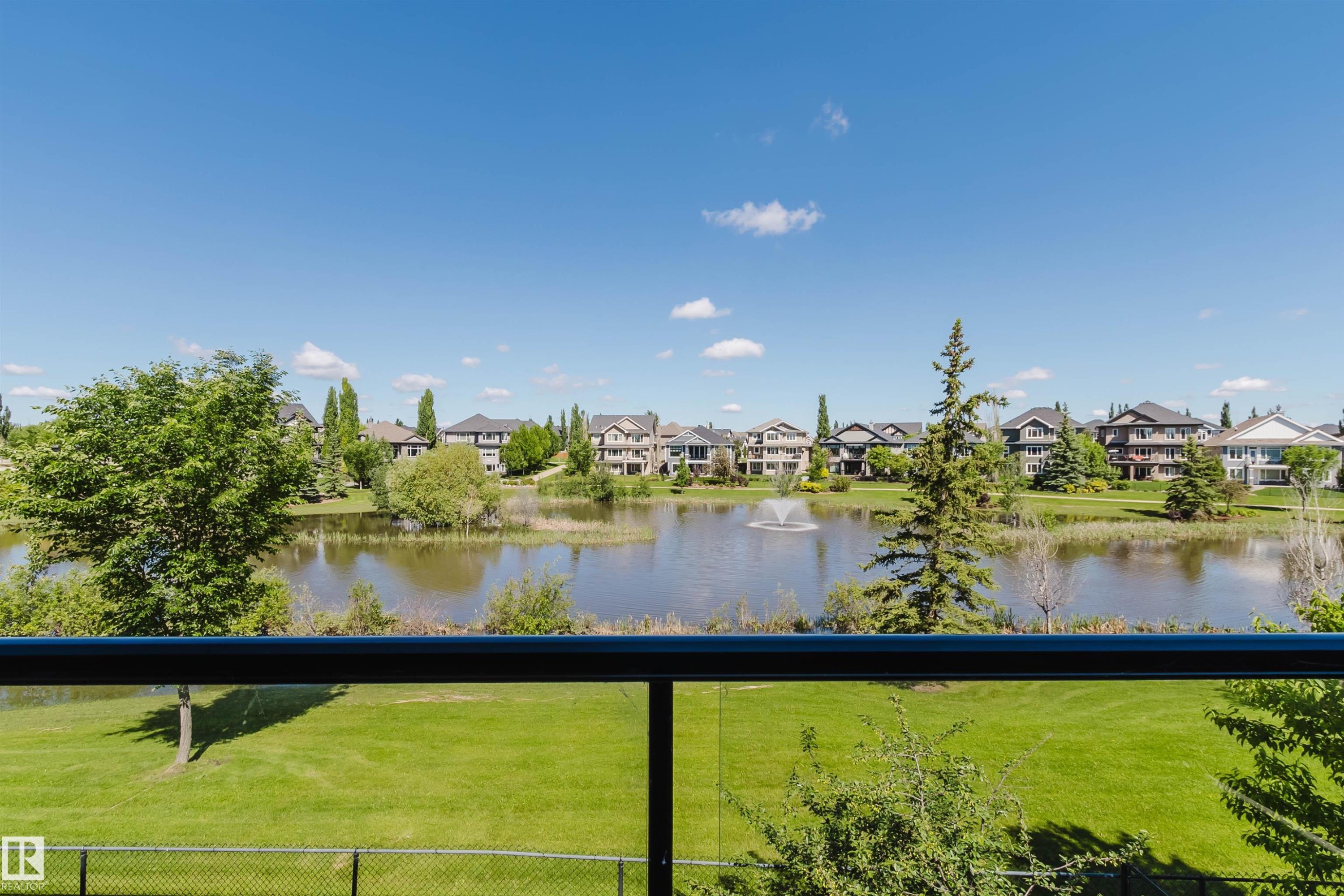 Expansive green space and a serene pond featuring a decorative fountain - 3438 West Landing Landing, Edmonton, AB