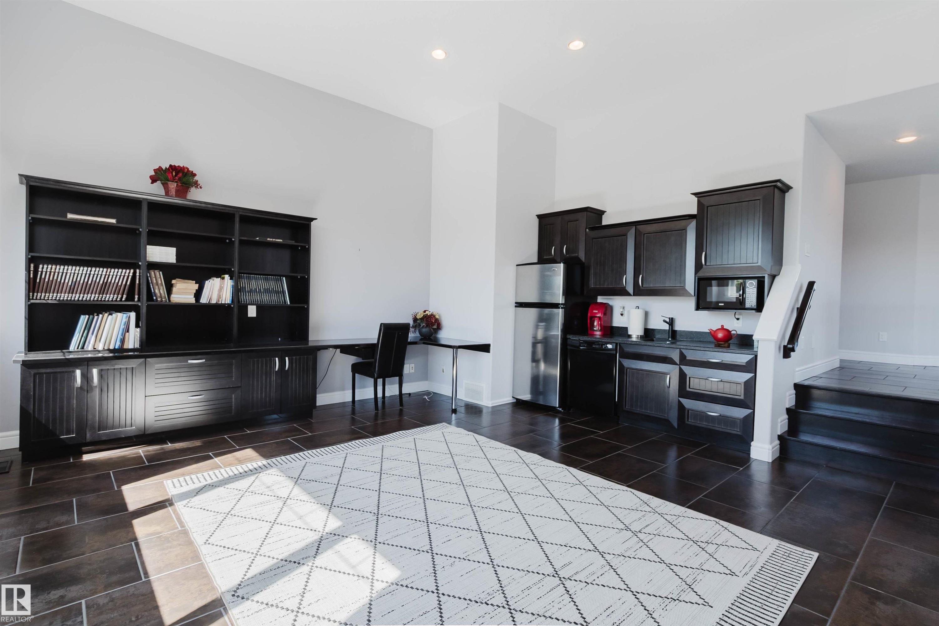 Versatile open concept space featuring expansive built-in shelving, a dedicated desk area, and a functional wet bar with stainless steel appliances - 3438 West Landing Landing, Edmonton, AB