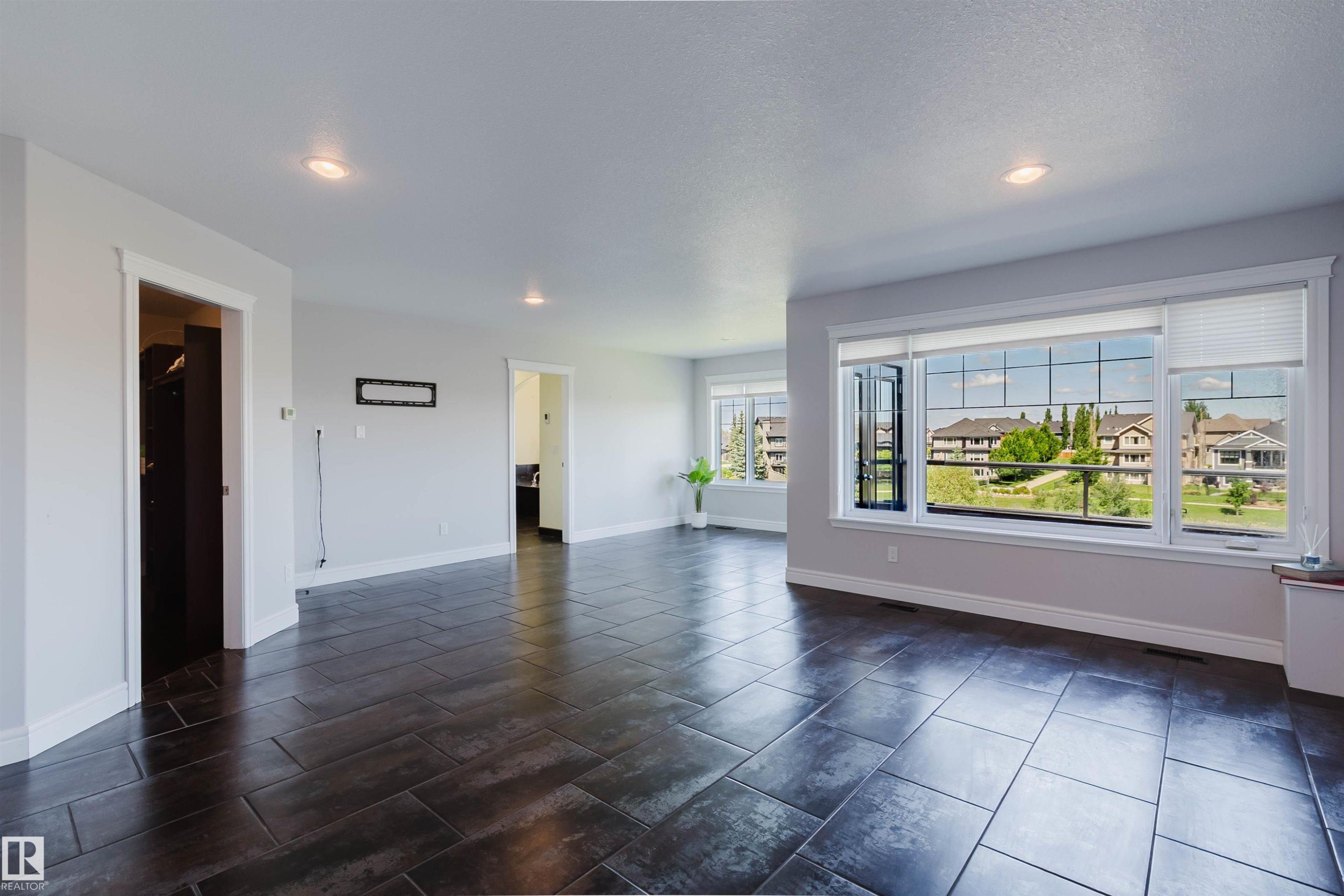 Spacious room featuring dark wood-finish tile flooring and light grey walls - 3438 West Landing Landing, Edmonton, AB