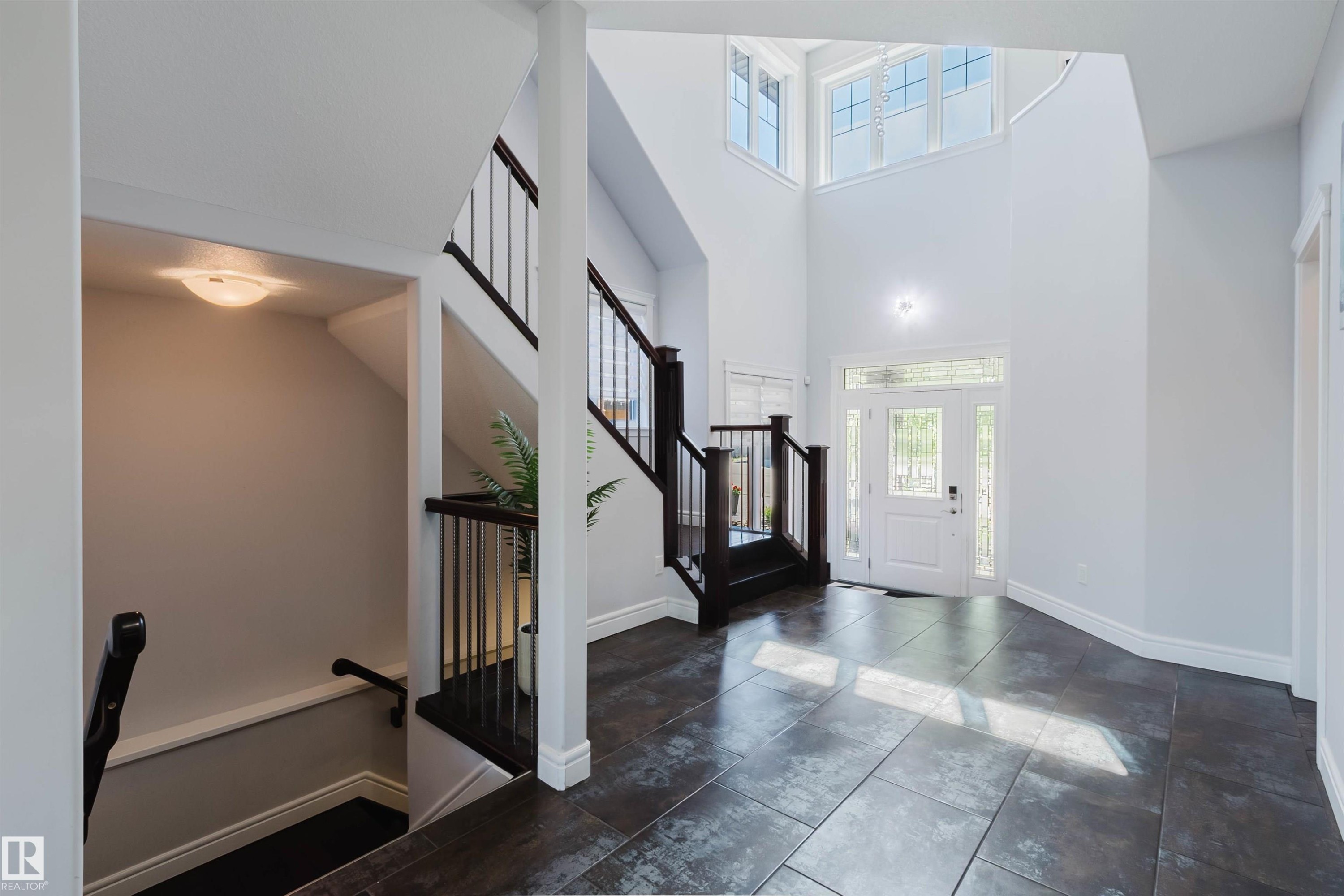 Bright entryway featuring a white paneled door with sidelights, transom windows, and dark tile flooring - 3438 West Landing Landing, Edmonton, AB