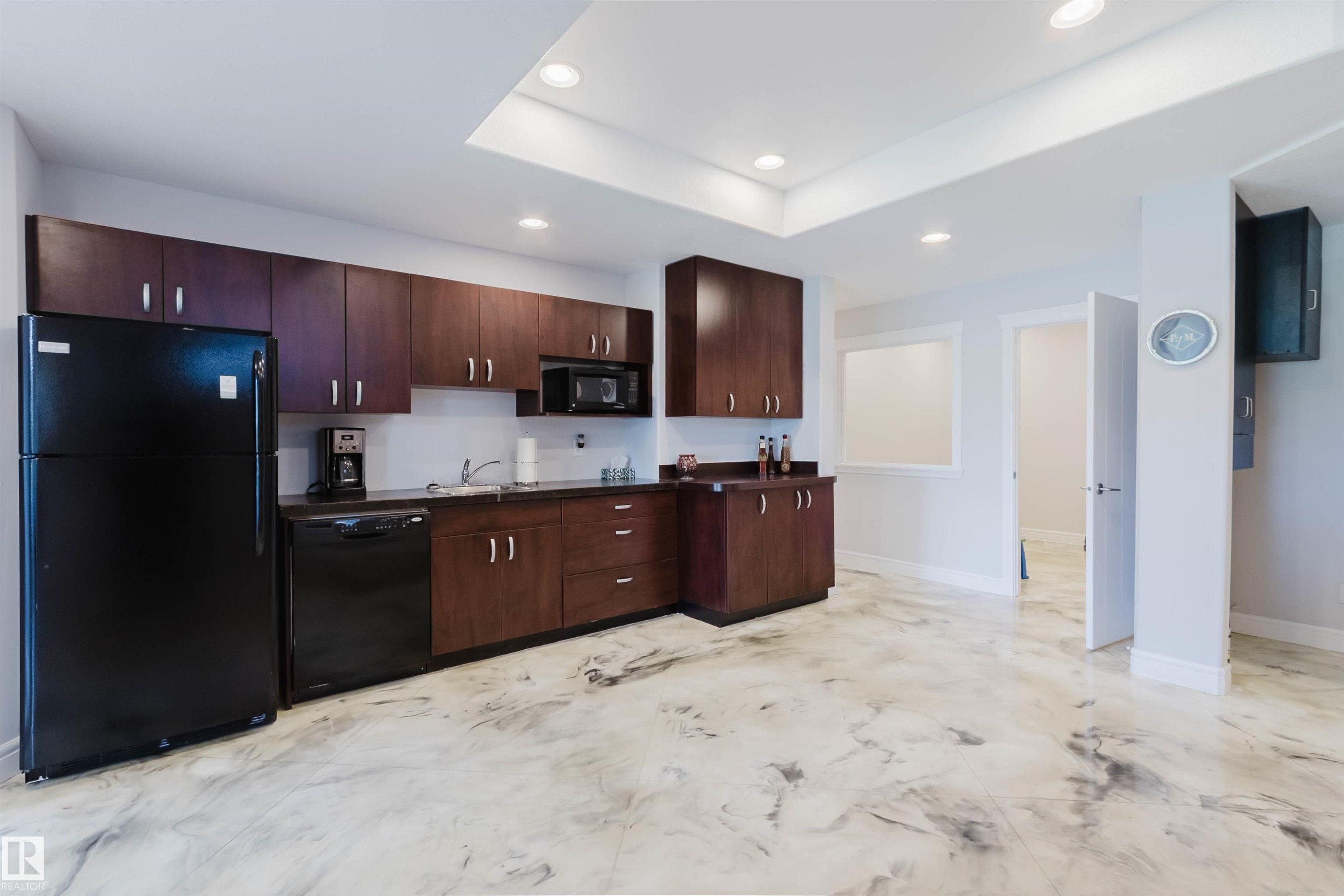 Kitchenette featuring dark wood cabinetry, black appliances, a stainless steel sink, and a dark countertop - 3438 West Landing Landing, Edmonton, AB