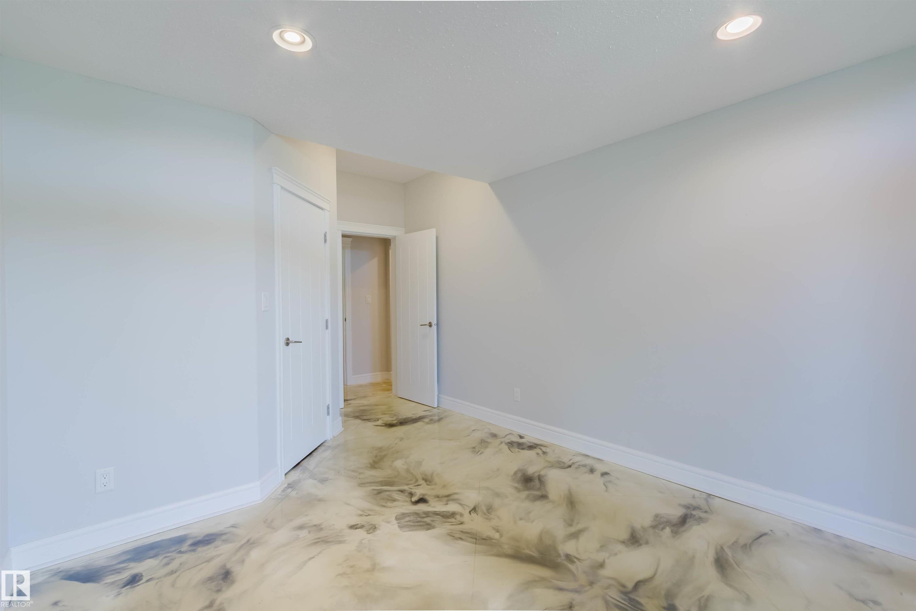 Spacious room featuring unique epoxy flooring with a marbled effect, recessed lighting, and white baseboards - 3438 West Landing Landing, Edmonton, AB