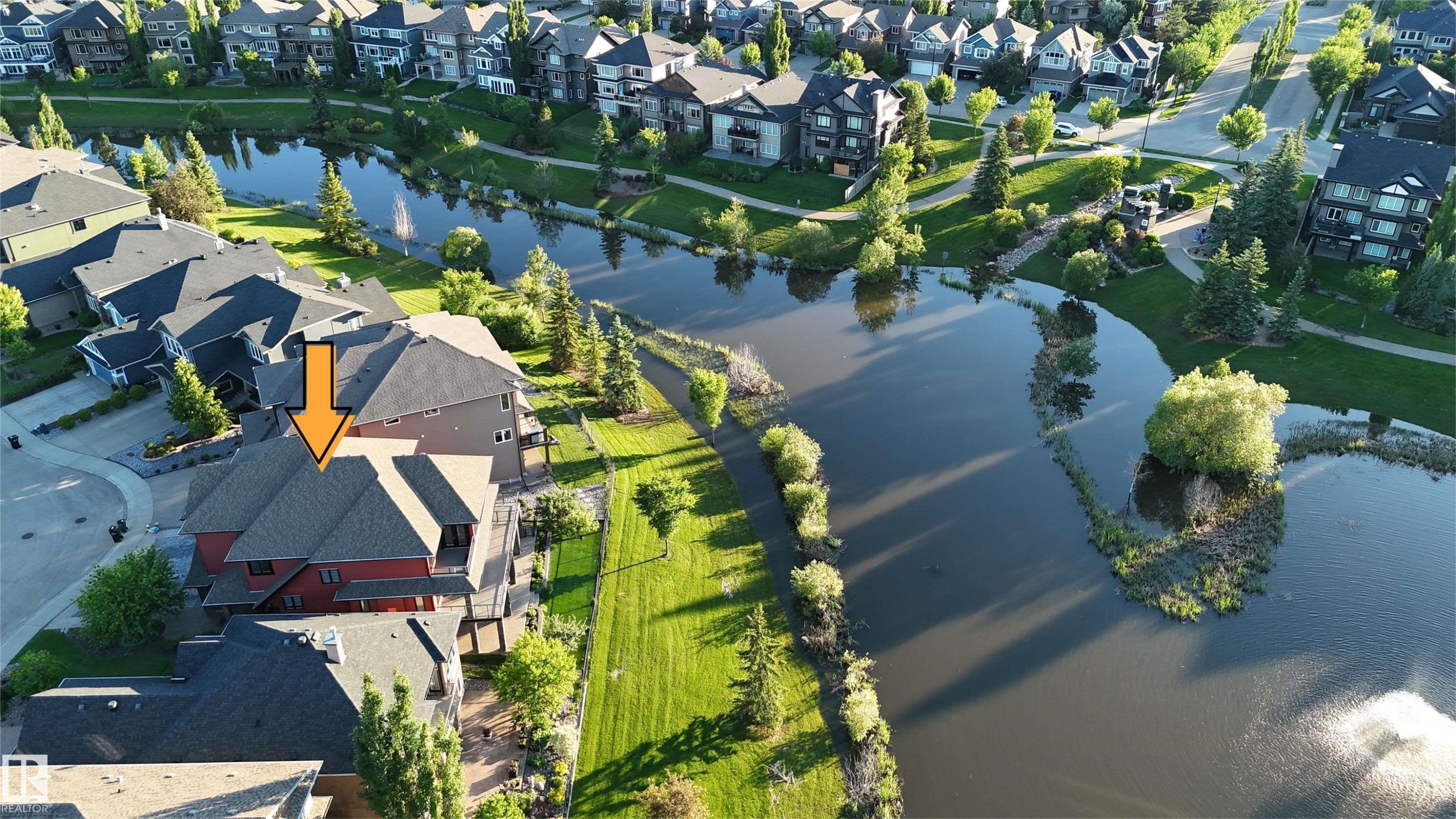 Waterside property with multi-level exterior, featuring a private deck, pitched roofline, and surrounding green space - 3438 West Landing Landing, Edmonton, AB