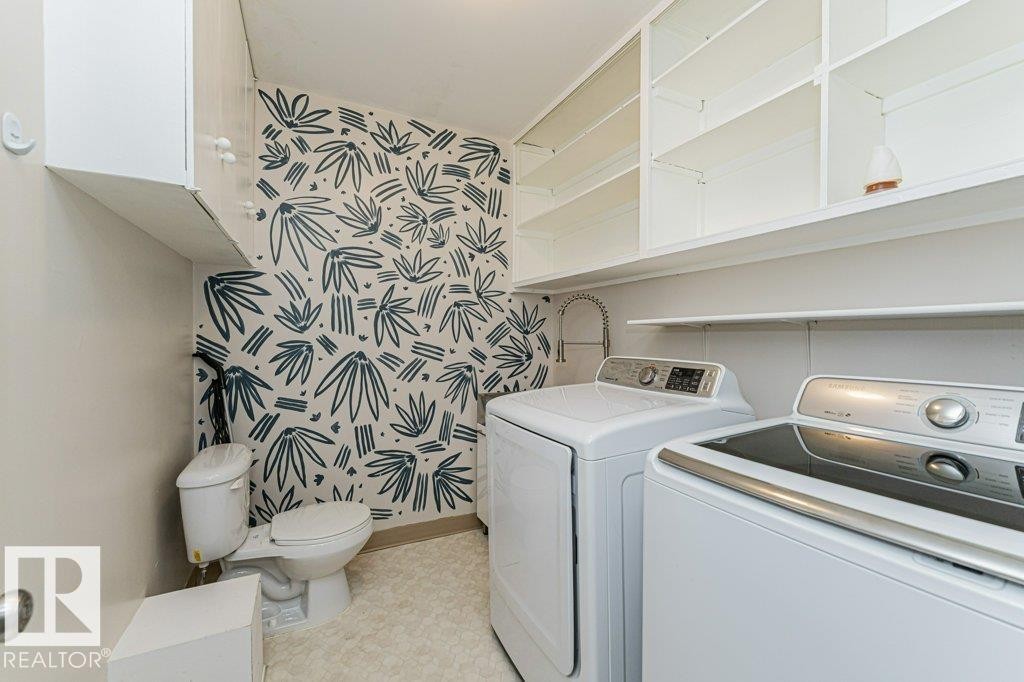 Laundry room featuring patterned wall covering, built-in shelving, white cabinetry, and a utility sink - 13411 140 Street, Edmonton, AB