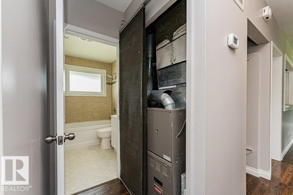 Bathroom featuring a white bathtub, toilet, and a window with privacy glass - 13411 140 Street, Edmonton, AB