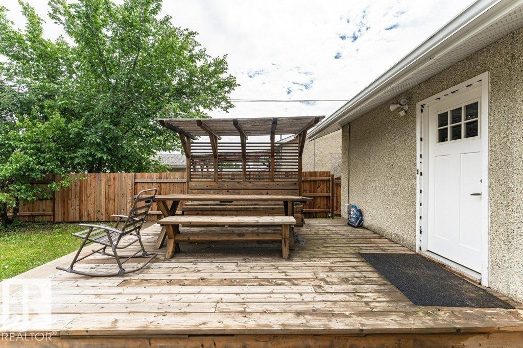 Expansive wood deck featuring a pergola, wood privacy fencing, and a white exterior door with window panes - 13411 140 Street, Edmonton, AB